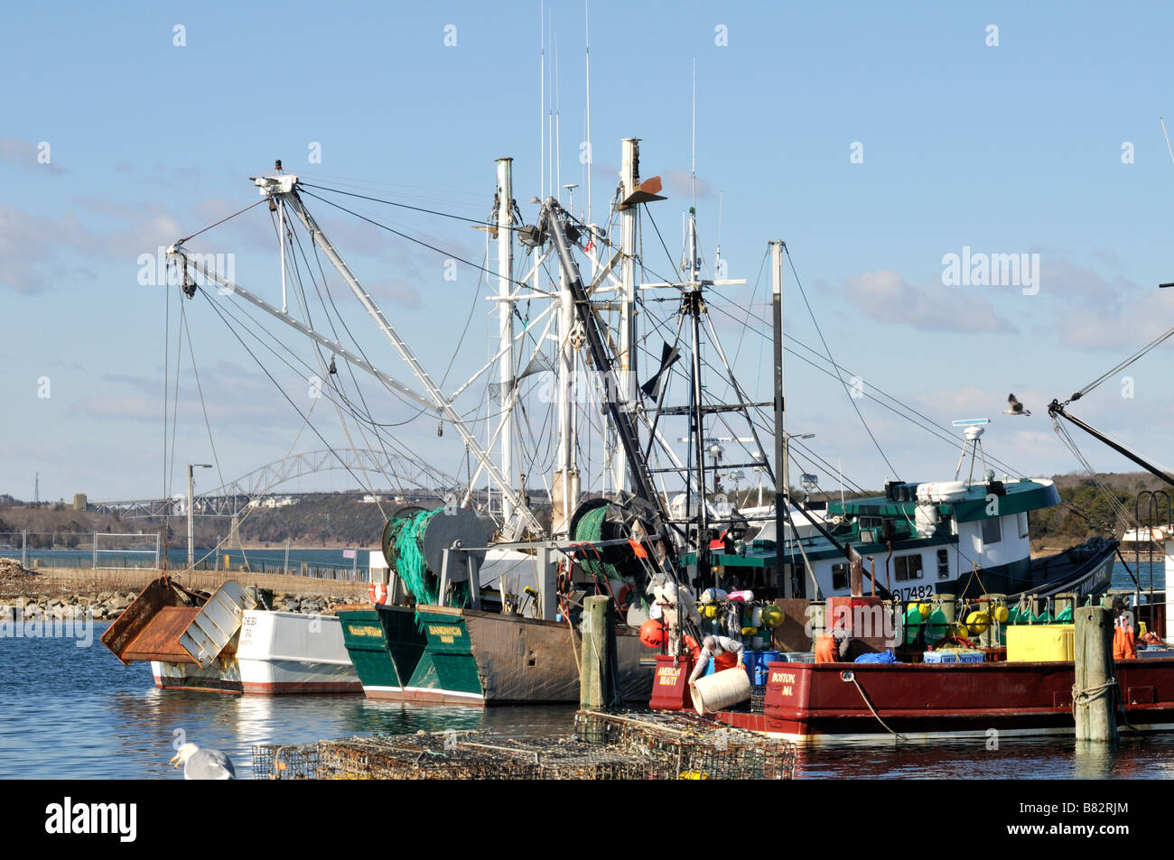 La pesca commerciale imbarcazioni al dock in Sandwich Marina Cape Cod con Sagamore Bridge a distanza Foto Stock