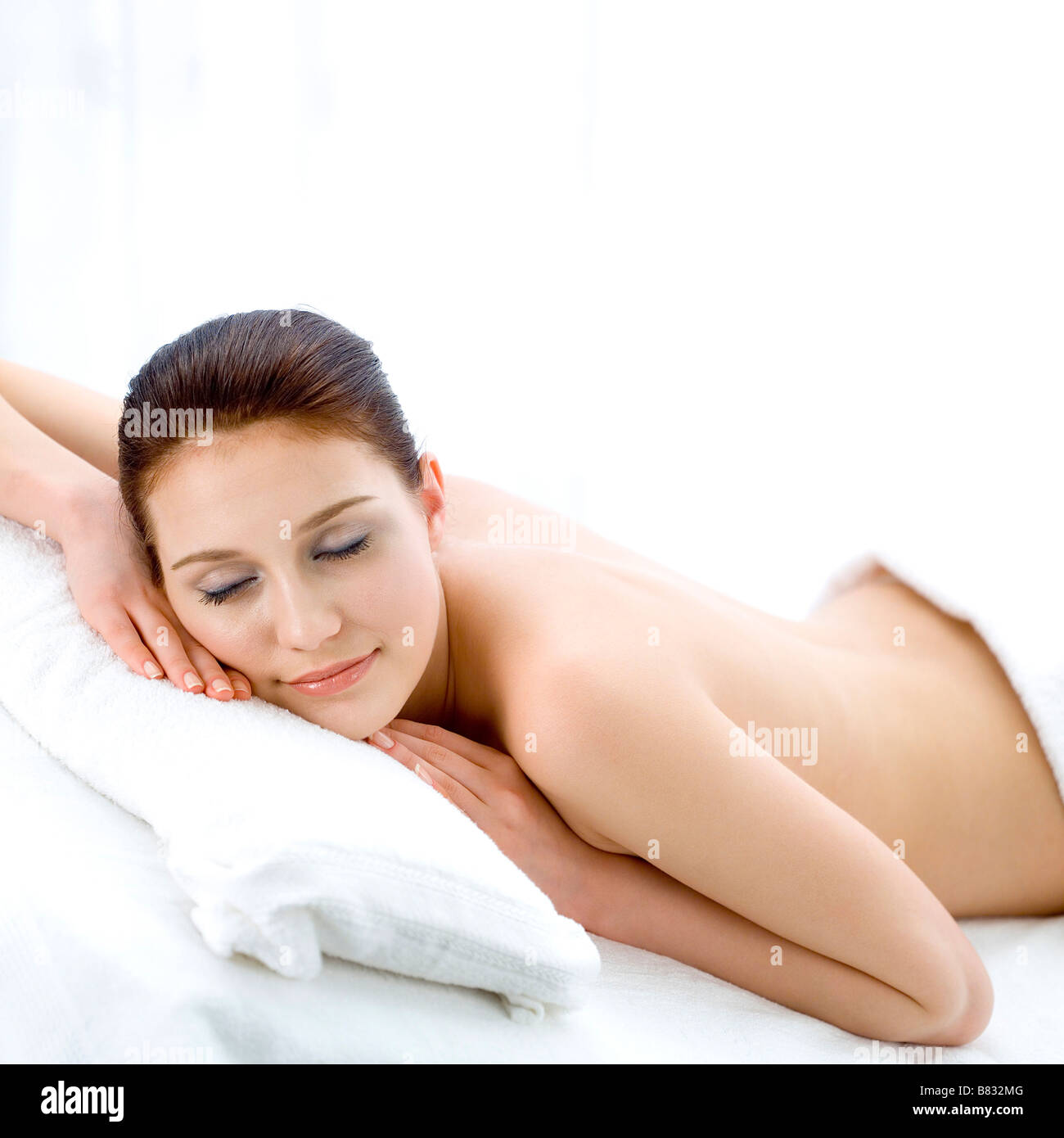 Giovane donna appoggiata in camera da letto gli occhi chiusi fino alla cintura Foto Stock