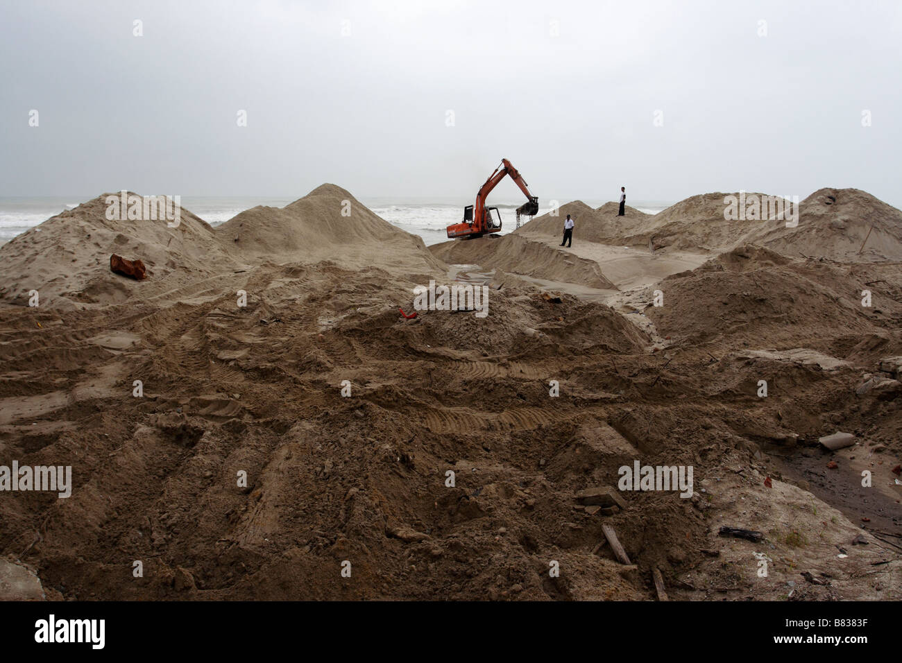 Un escavatore lavorando sulla spiaggia sabbiosa a Kuala Terengganu, Malaysia. Foto Stock