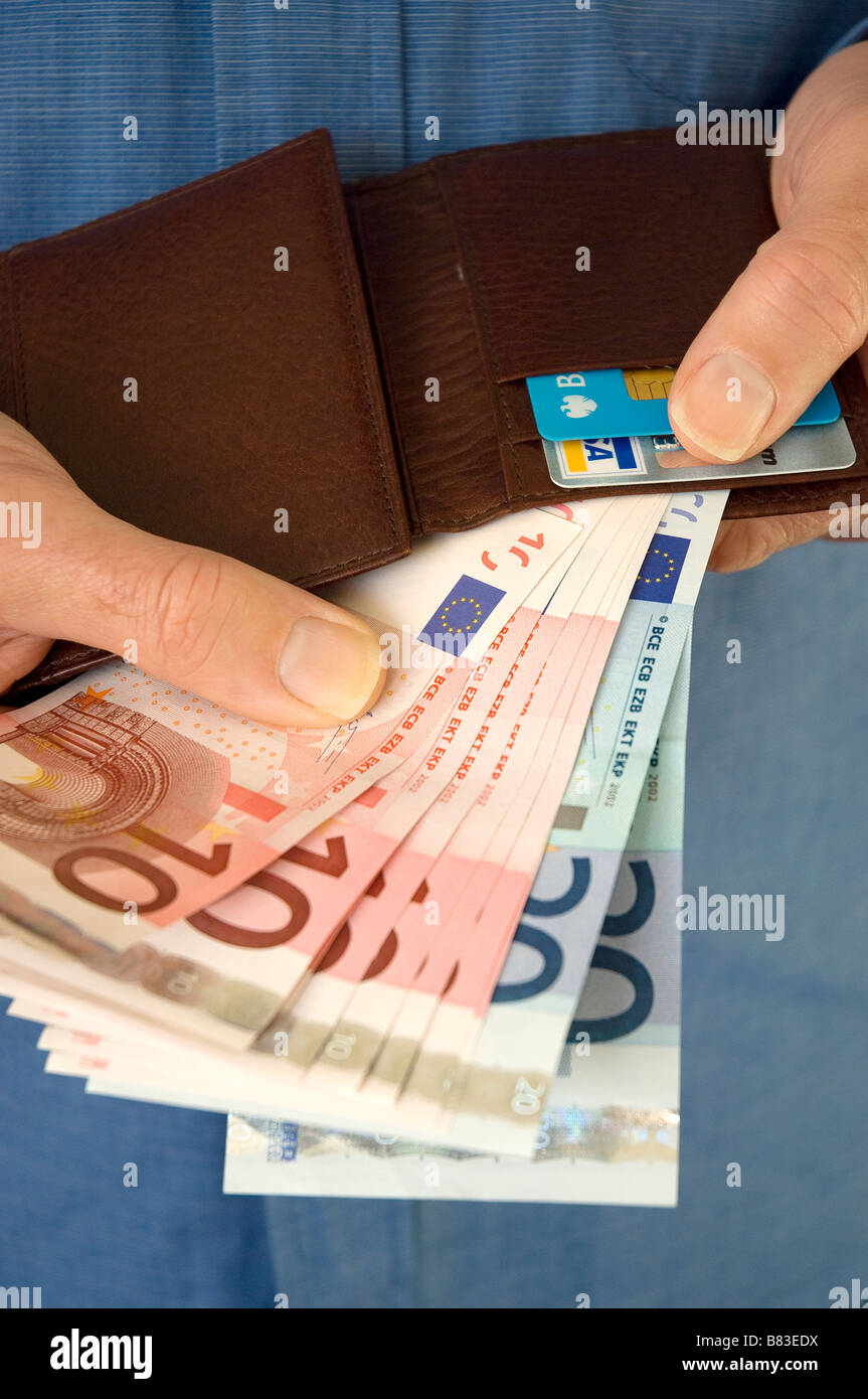 Primo piano di uomo che tiene banconote e portafogli in euro Foto Stock