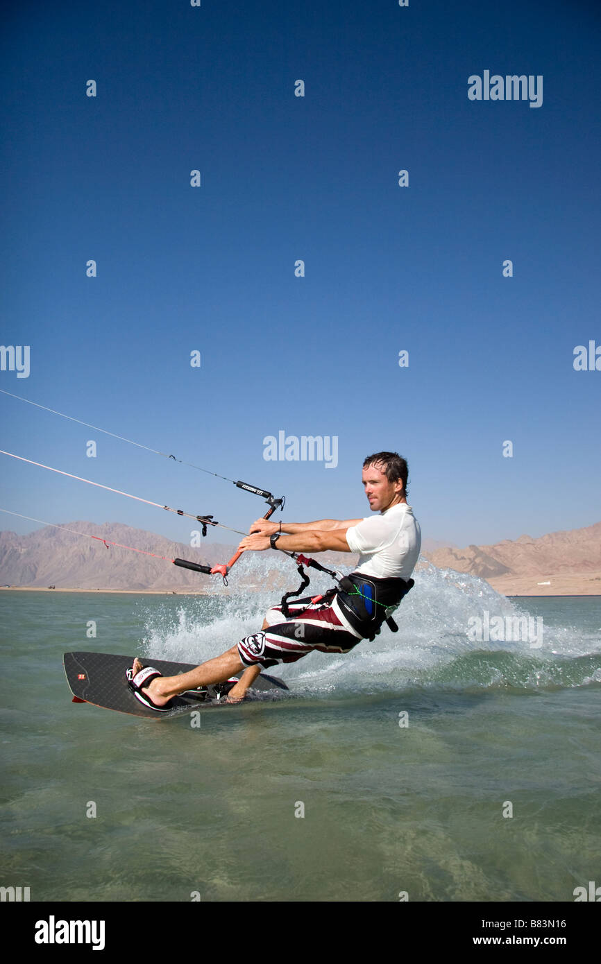Un kitesurfer attraversa il turchese acqua piatta laguna (QURA BAY) all'interno della sabbia sputa nel Sinai resort di Dahab in Egitto Foto Stock