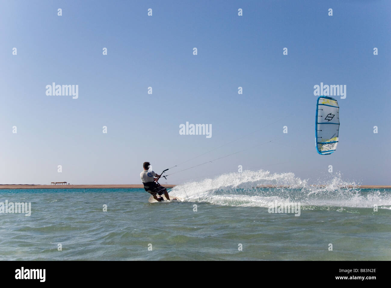 Un kitesurfer attraversa il turchese acqua piatta laguna (QURA BAY) all'interno della sabbia sputa nel Sinai resort di Dahab in Egitto Foto Stock
