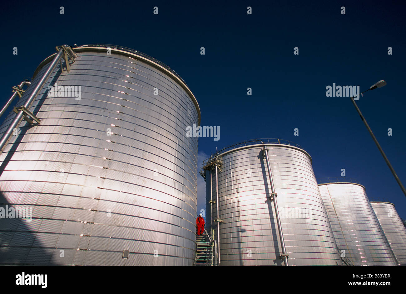 Un responsabile della sicurezza cammina giù le scale di ispezione su serbatoi di stoccaggio ad un impianto di olio Kazakistan Foto Stock