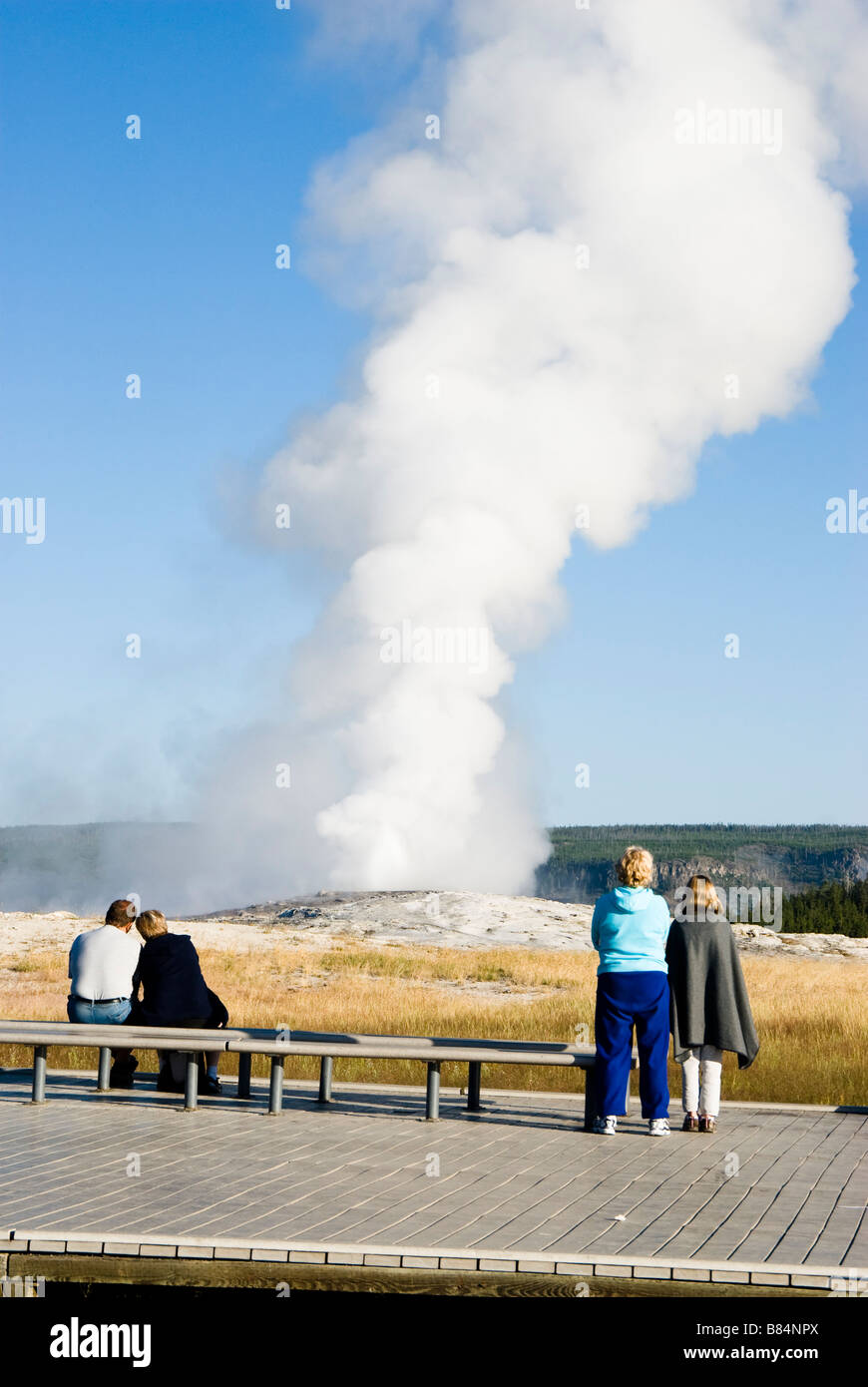 I turisti a guardare come il vecchio Fathful geyser erutta nel Parco Nazionale di Yellowstone Foto Stock