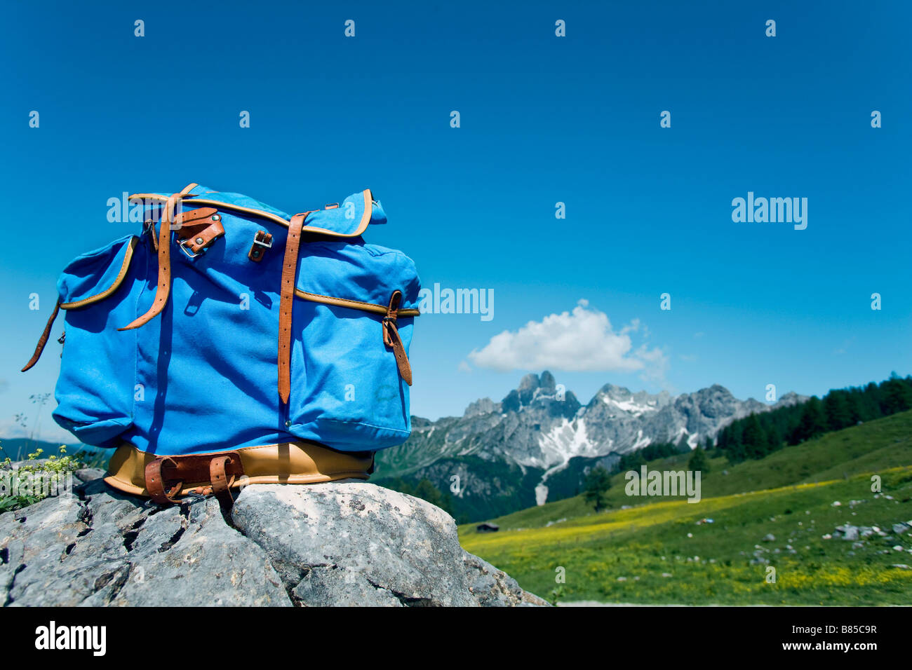 Zaino blu sulla roccia di fronte montagne Foto Stock
