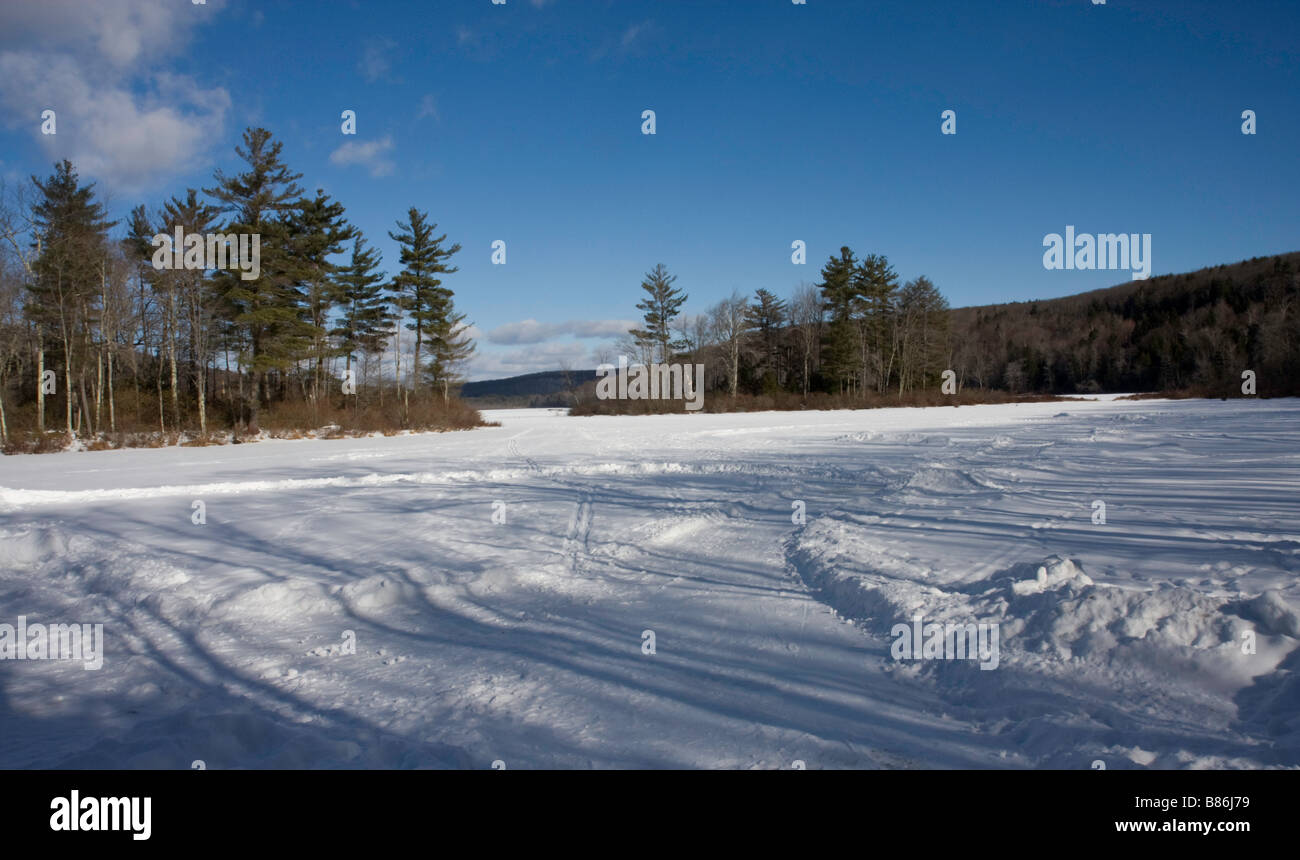 Lago ghiacciato con copertura di neve fresca e i cingoli del trattore da motoslitte e persone a pattinare sulla superficie ghiacciata in Connecticut Foto Stock