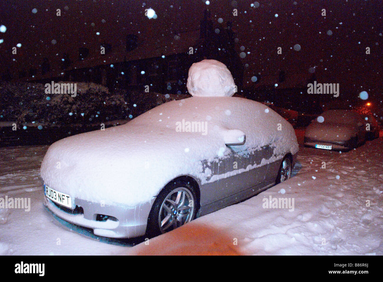 Auto parcheggiata con una gigantesca palla di neve sul tetto! Foto Stock