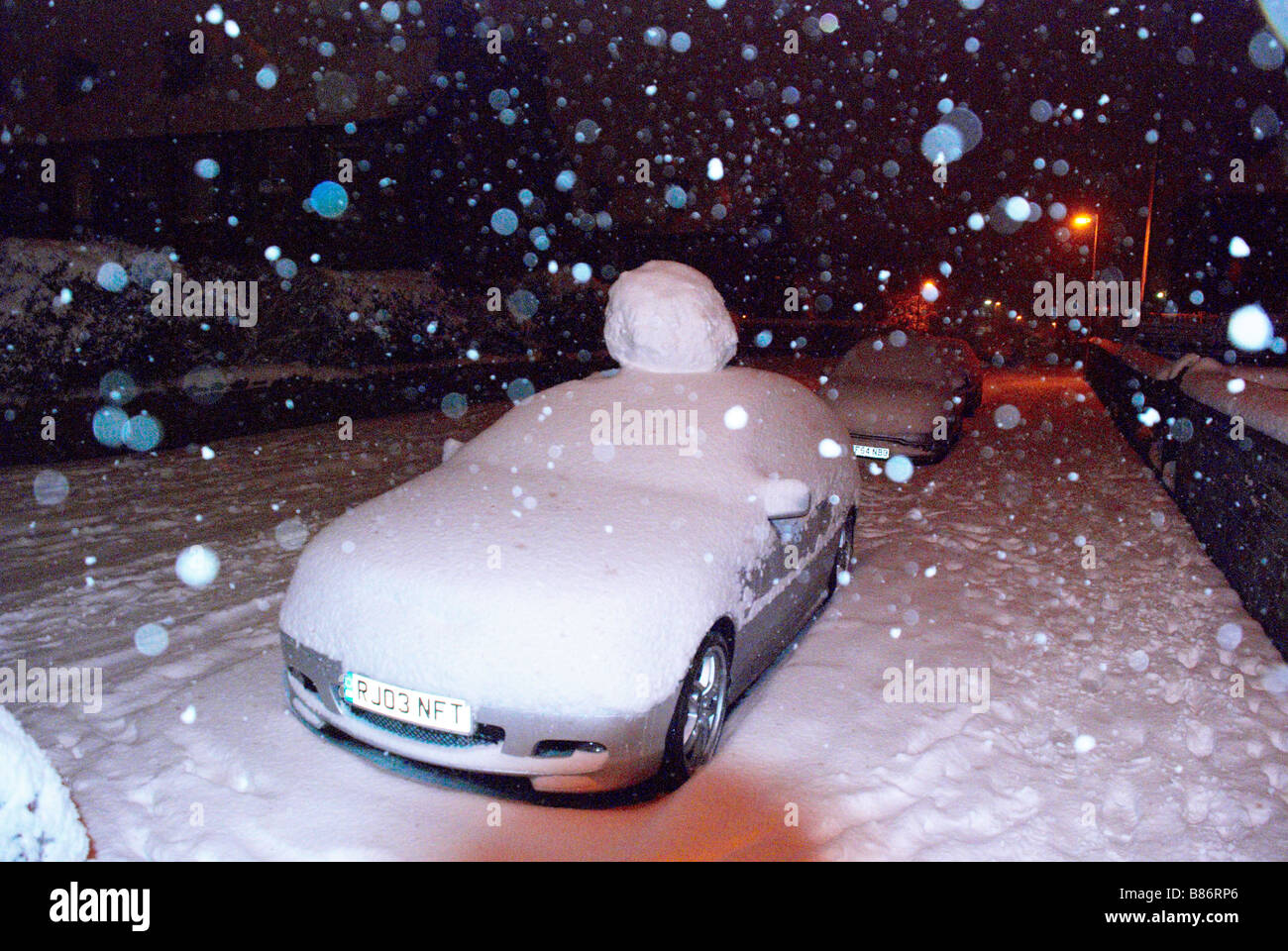 Auto parcheggiata con una gigantesca palla di neve sul tetto! Foto Stock