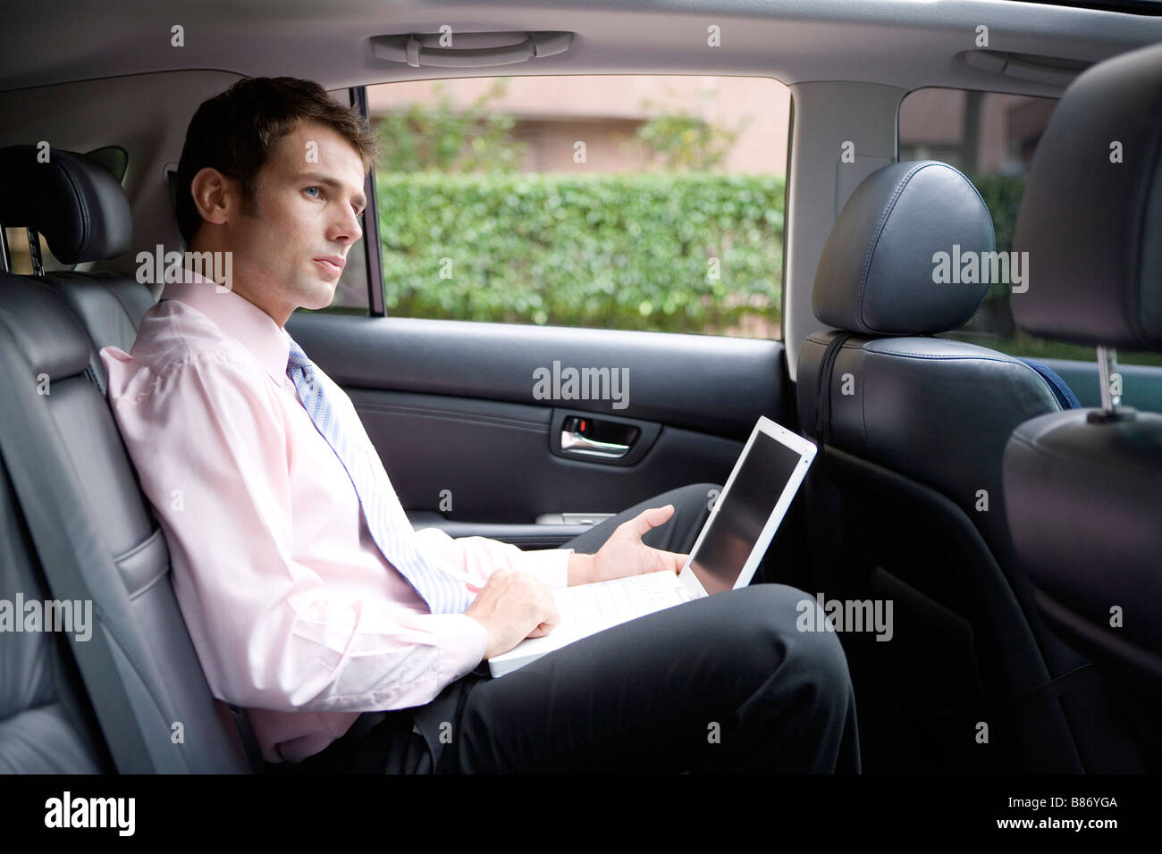Uomo d affari con computer portatile in auto Foto Stock