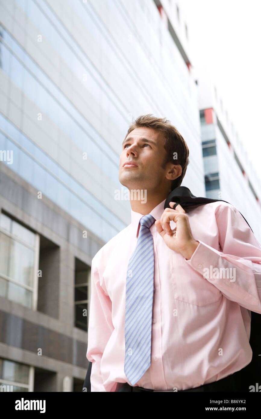 Imprenditore camminando sulla strada con camicia sul retro che si affaccia su vista dal basso Foto Stock