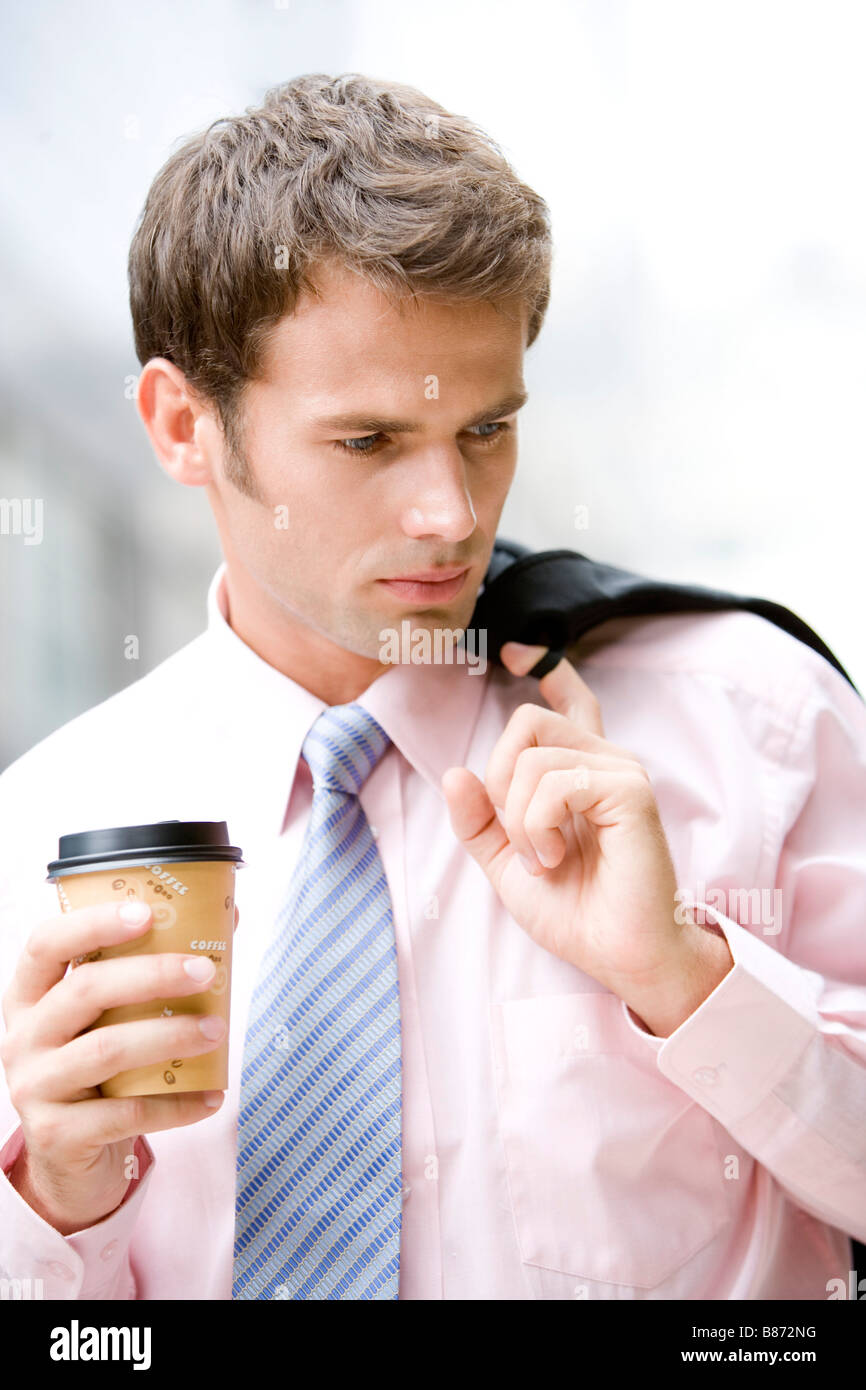 Imprenditore azienda tazza da caffè guardando lontano da vicino Foto Stock