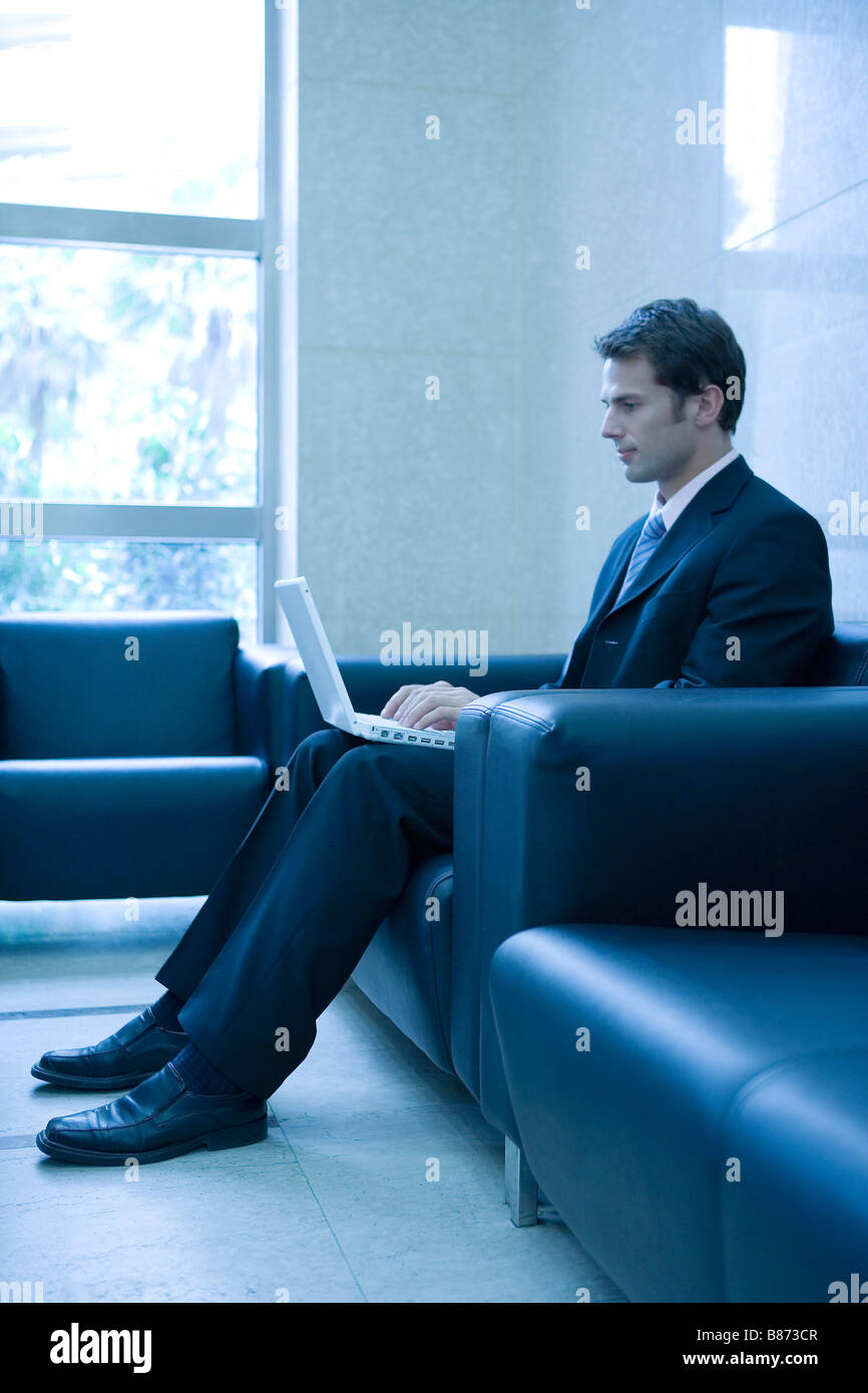 Uomo d affari con computer portatile sul divano vista laterale Foto Stock