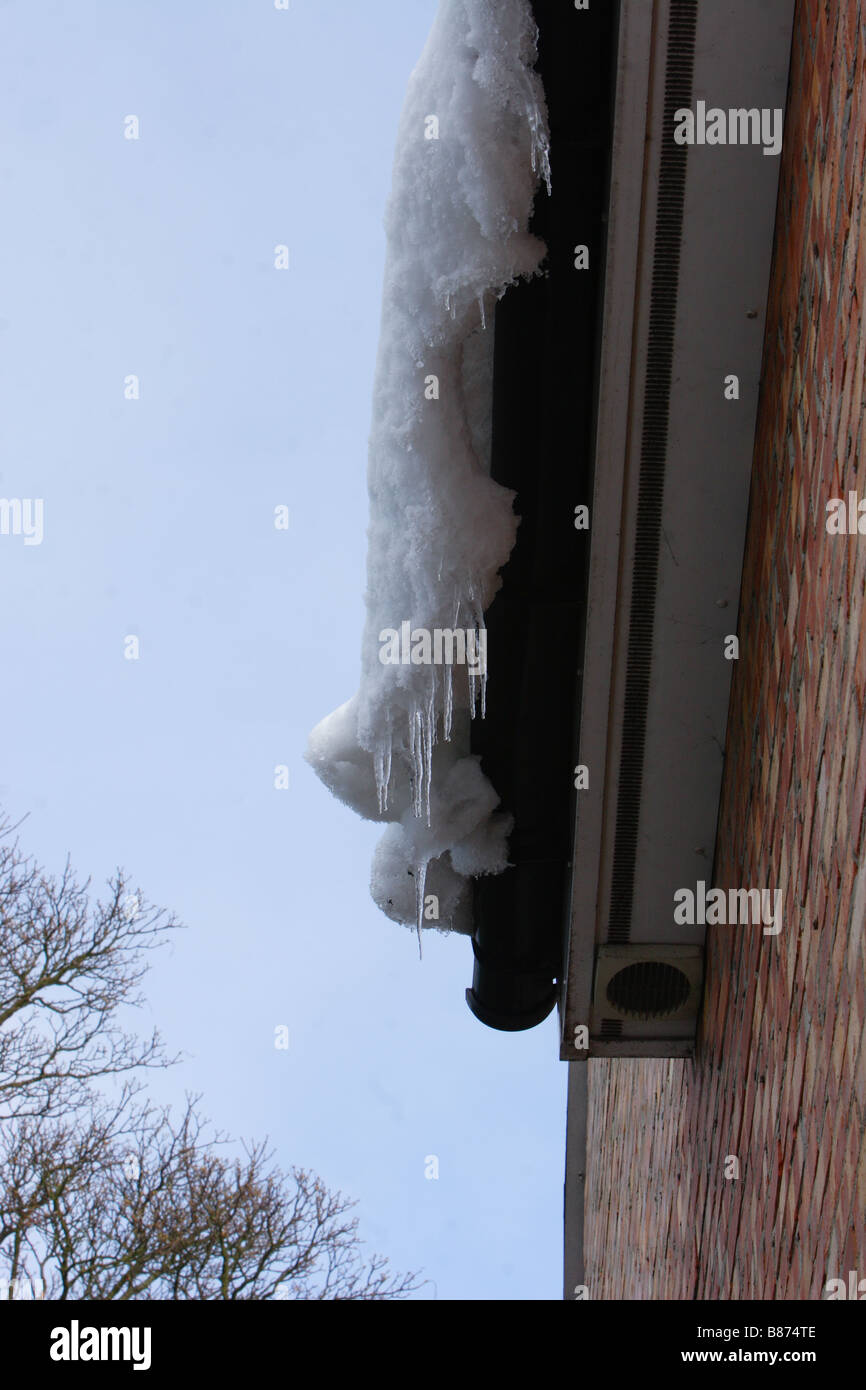 Neve di fusione a sbalzo di un tetto di casa Foto Stock