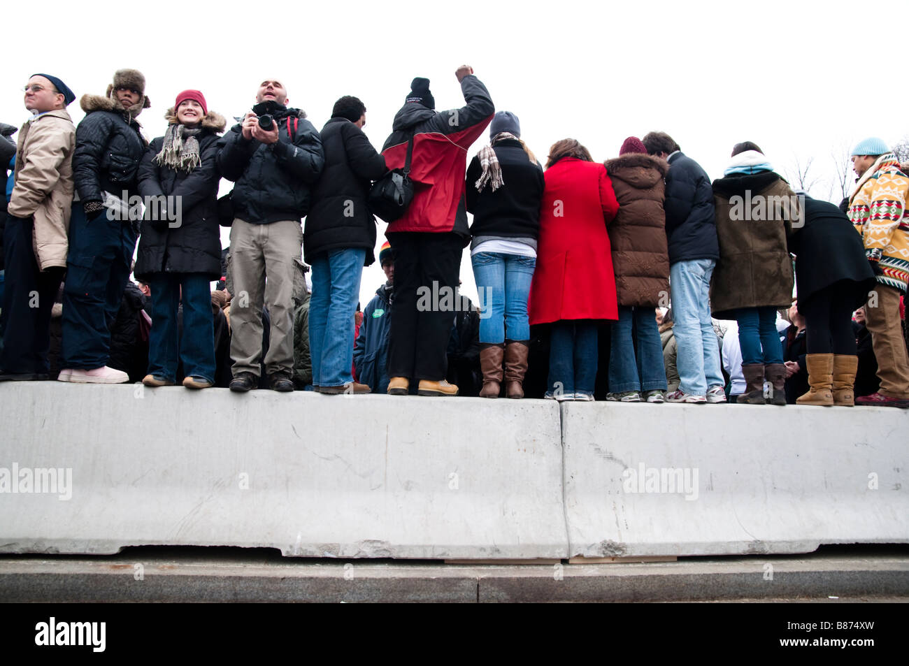 Persone appollaiarsi su una parete per una migliore vista sopra la folla ad un concerto per celebrare la cerimonia di insediamento del Presidente Barack Obama Foto Stock
