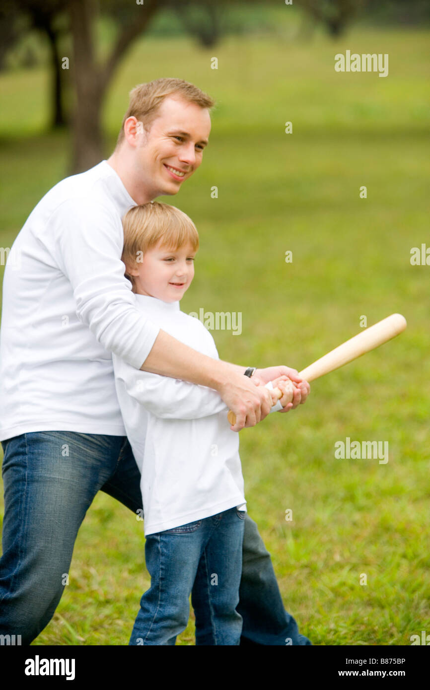 Giovane uomo insegnare a suo figlio di bat Foto Stock