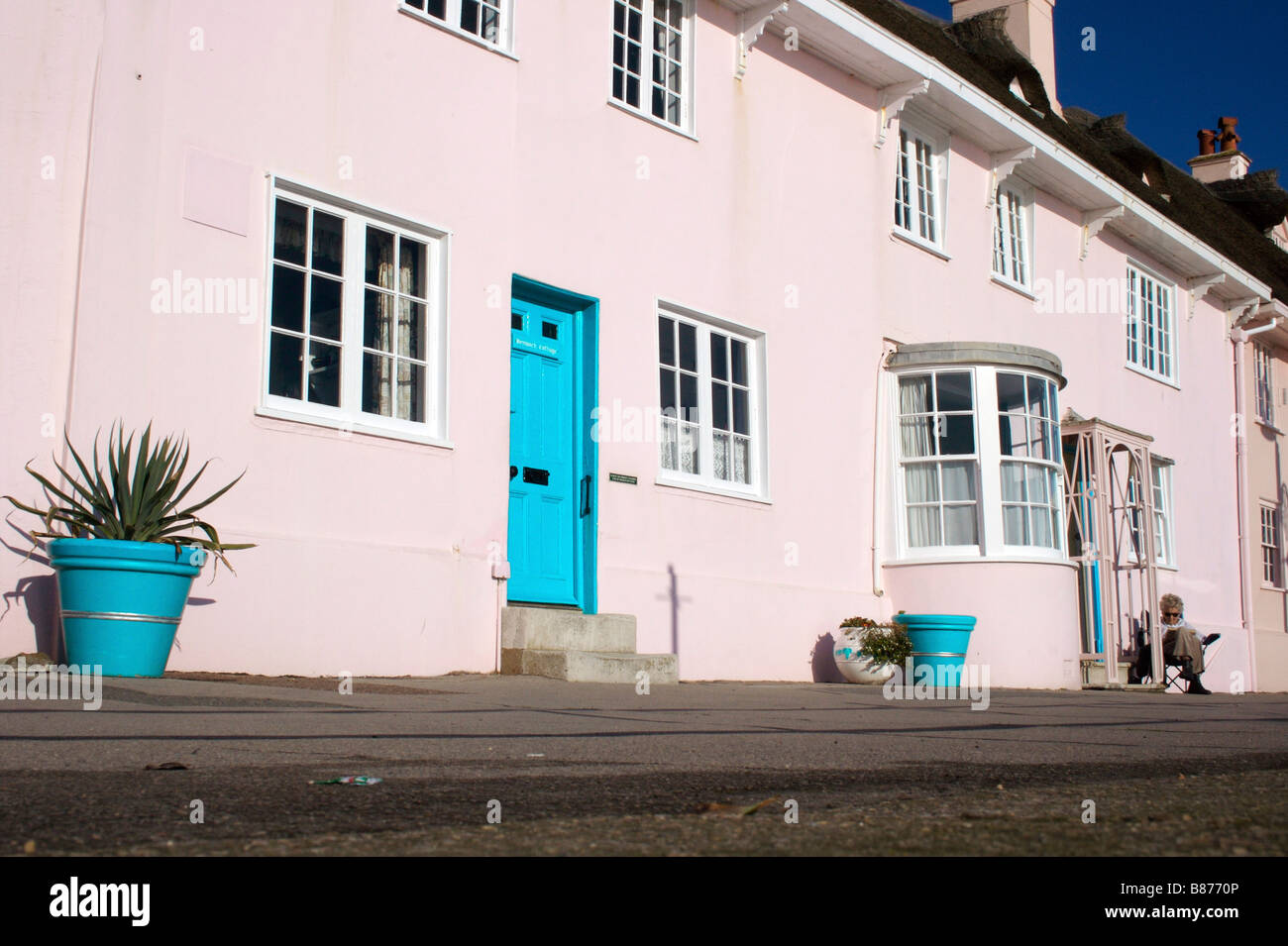 Signora Lettura da casa rosa sul lungomare di Lyme Regis Foto Stock