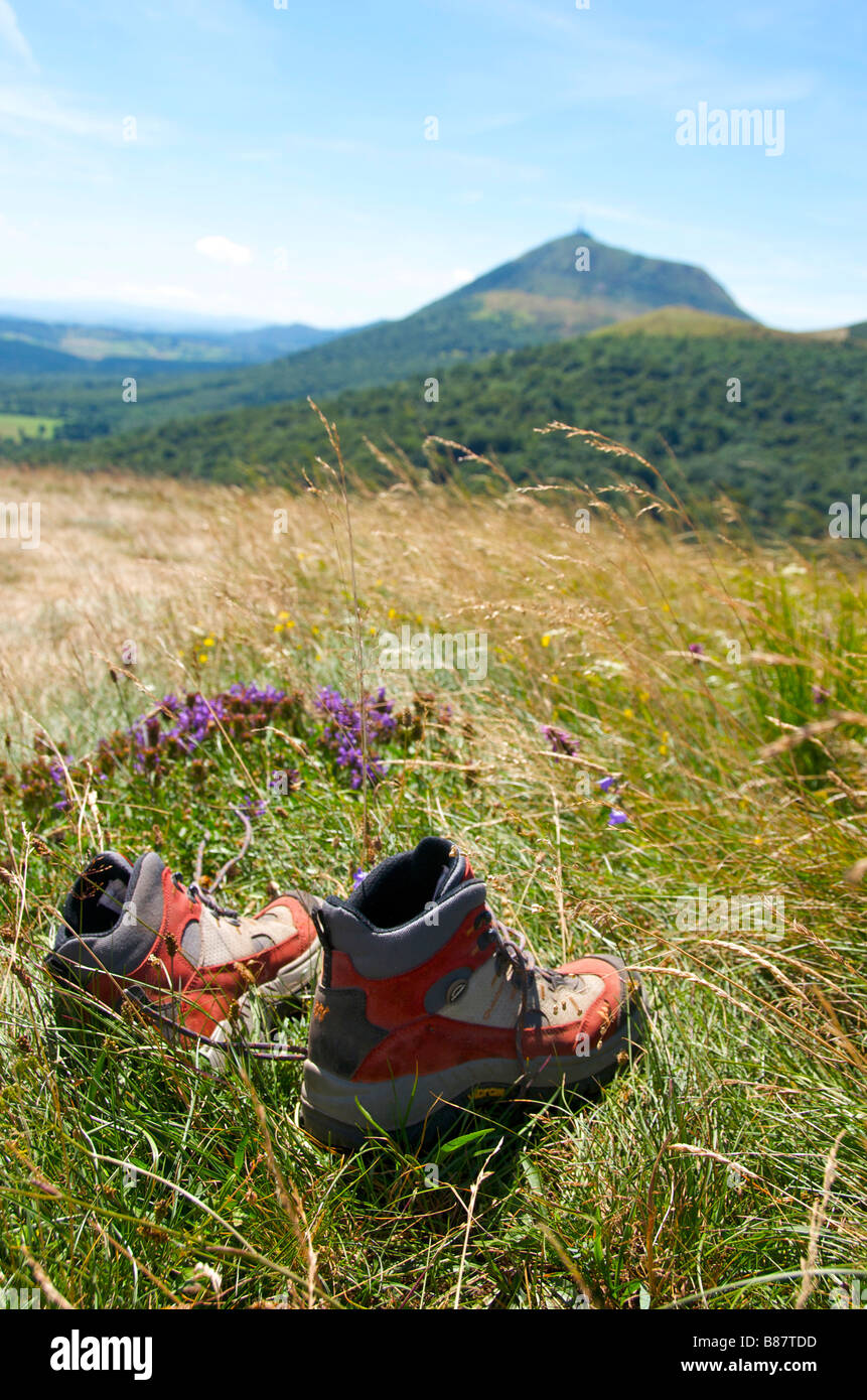 Scarpe da trekking in un campo di fronte al massiccio del Puy de Dome / Puy-de-Dome, Auvergne, Francia Foto Stock