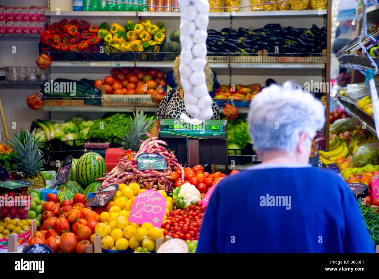 Una donna anziana negozi per le verdure in una produzione di stand a Venezia Italia Foto Stock