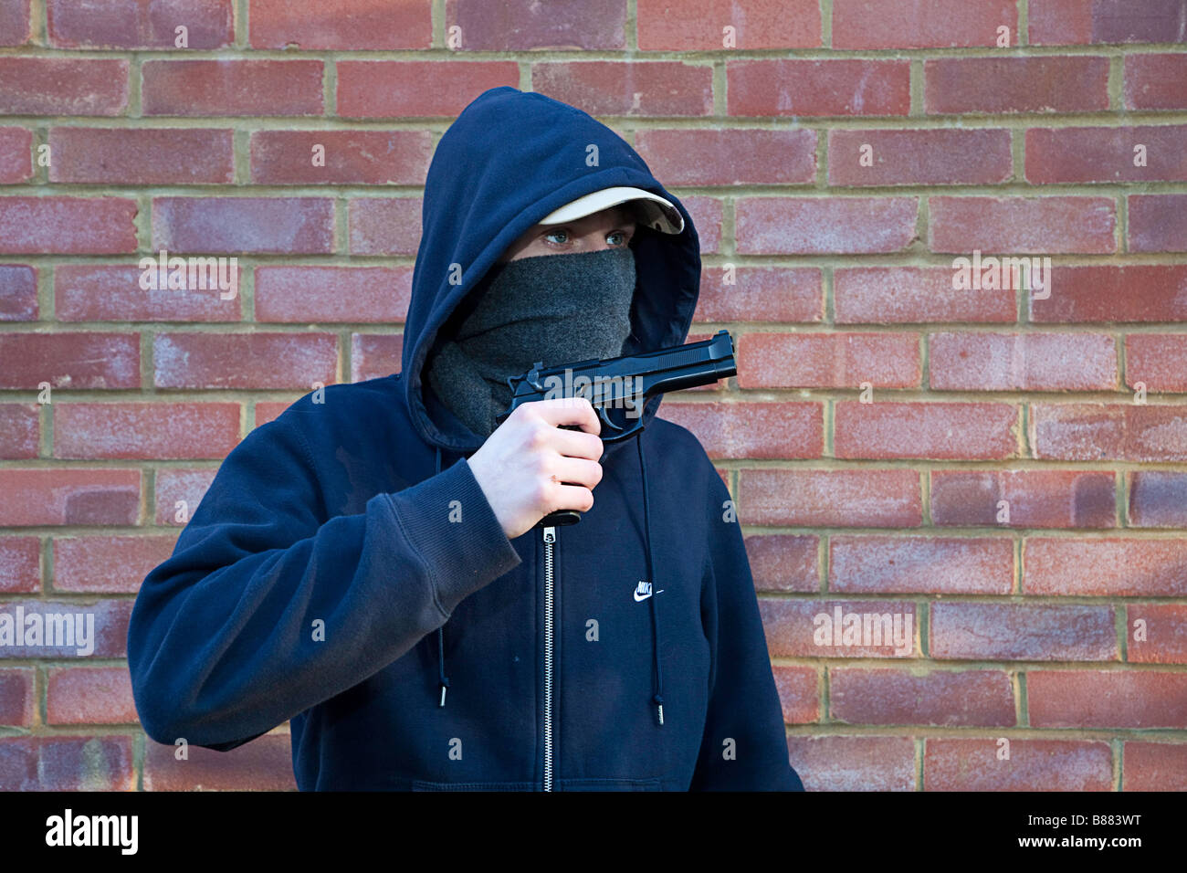 Pista pistola criminalità - incappucciati adolescente mascherato mostra con orgoglio il suo Beretta 92 pistola Foto Stock