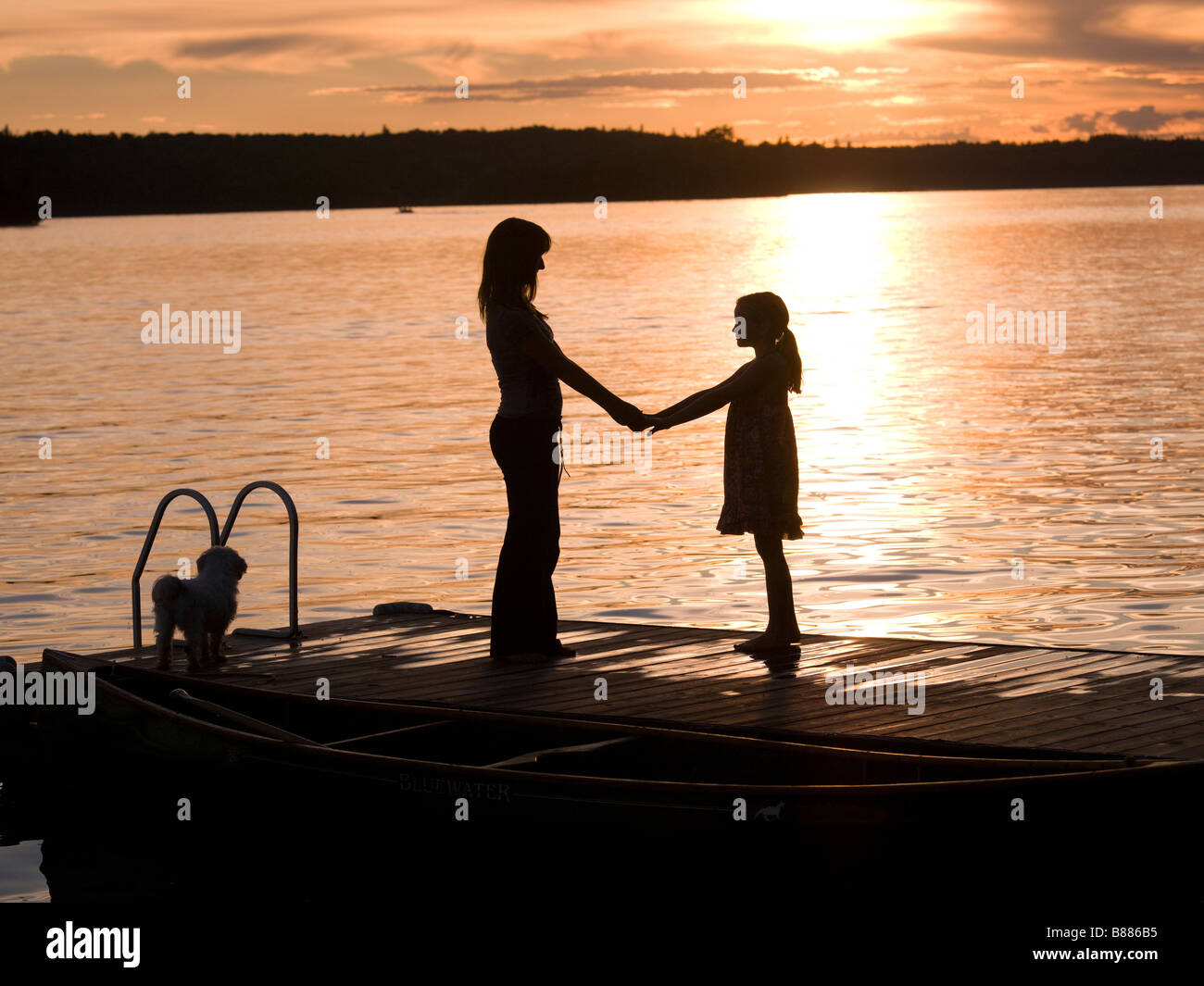 Silhouette di madre e figlia su un dock, il lago dei boschi, Ontario, Canada Foto Stock