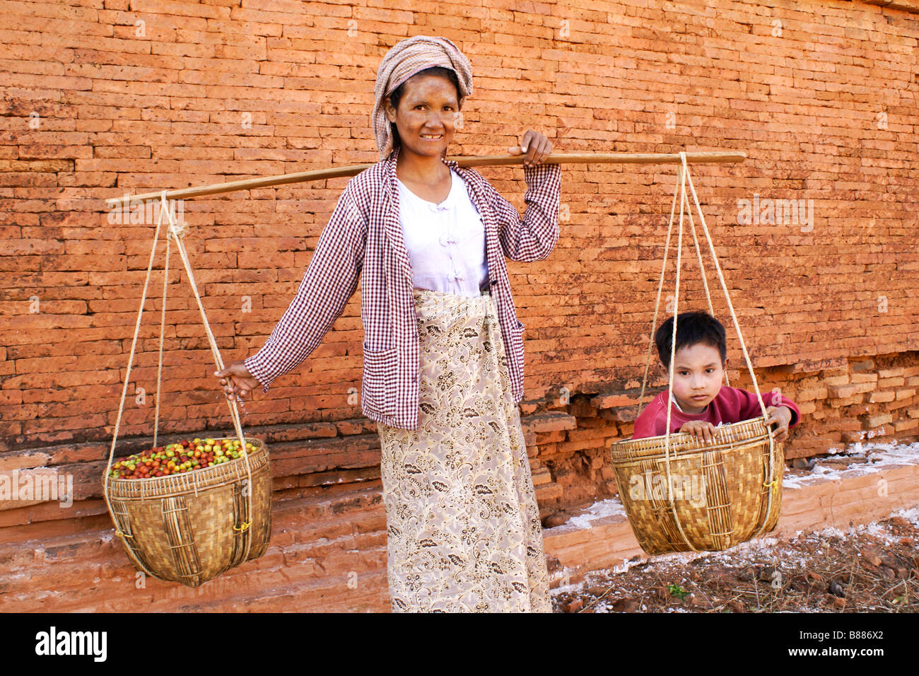 La donna che porta il figlio e la frutta in ceste, Bagan (pagano), Myanmar (Birmania) Foto Stock