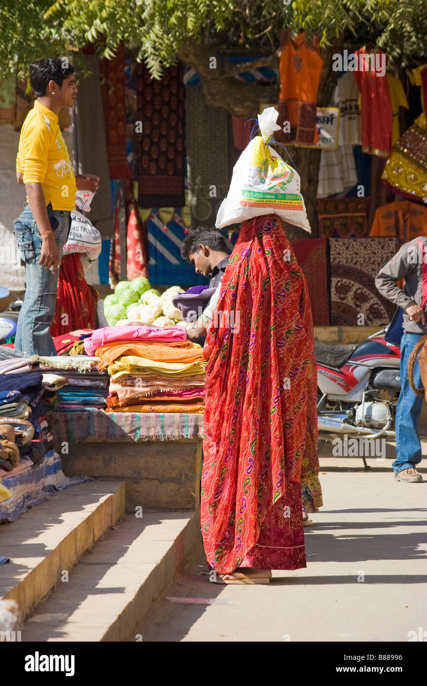 Donna indiana porta sacco in testa nel mercato Jaisalmer Rajasthan in India Foto Stock