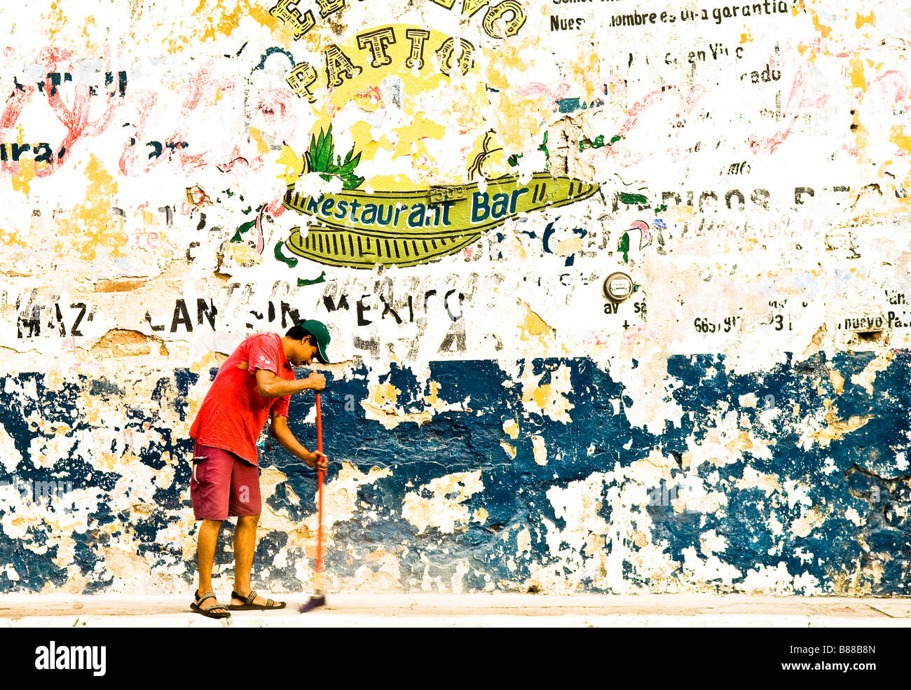 L'uomo spazzare il marciapiede e sbiadita segni sulla parete Avenida Zaragoza città vecchia Mazatlan Messico Foto Stock