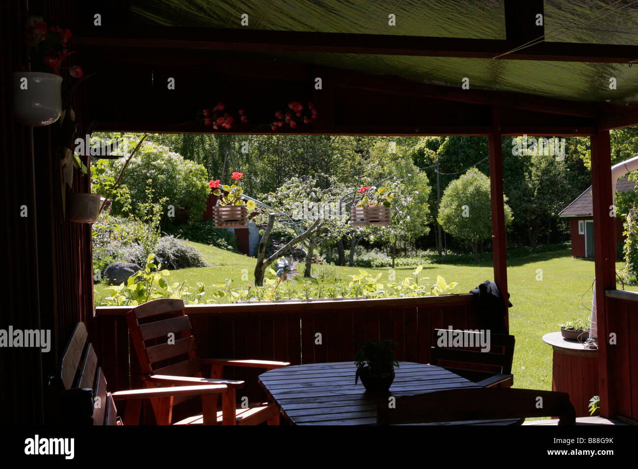 Vista da una veranda ombreggiata con giardino estivo sullo sfondo in Svezia. Foto Stock
