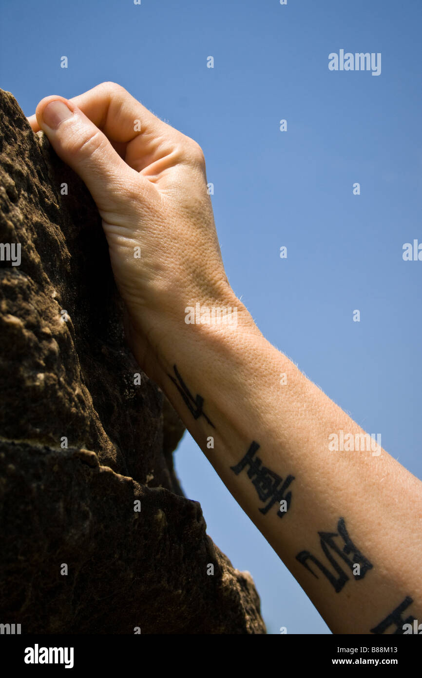 Canto femminile di scalatore che arrivano fino ad una messa in attesa su una parete di roccia. Foto Stock