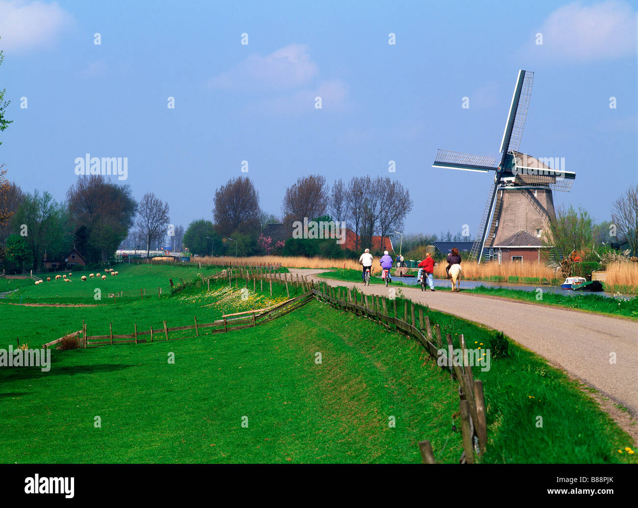 Equitazione per bambini di carretti e pony e biciclette sul rurale elevata canal road in Olanda ultimi mulini a vento e fattorie Foto Stock