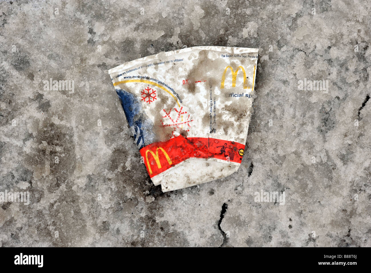 Schiacciato scartato cucciolata macdonalds cup un fast food drink neve sporca di terra cruda inverno packaging company negativo di business Foto Stock