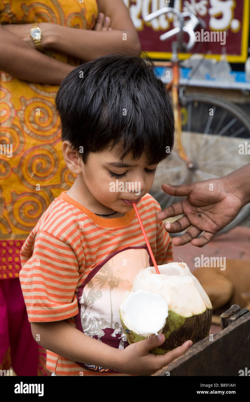 Ragazzo di bere latte di cocco da un cocco fresco, in Mumbai. India. Foto Stock