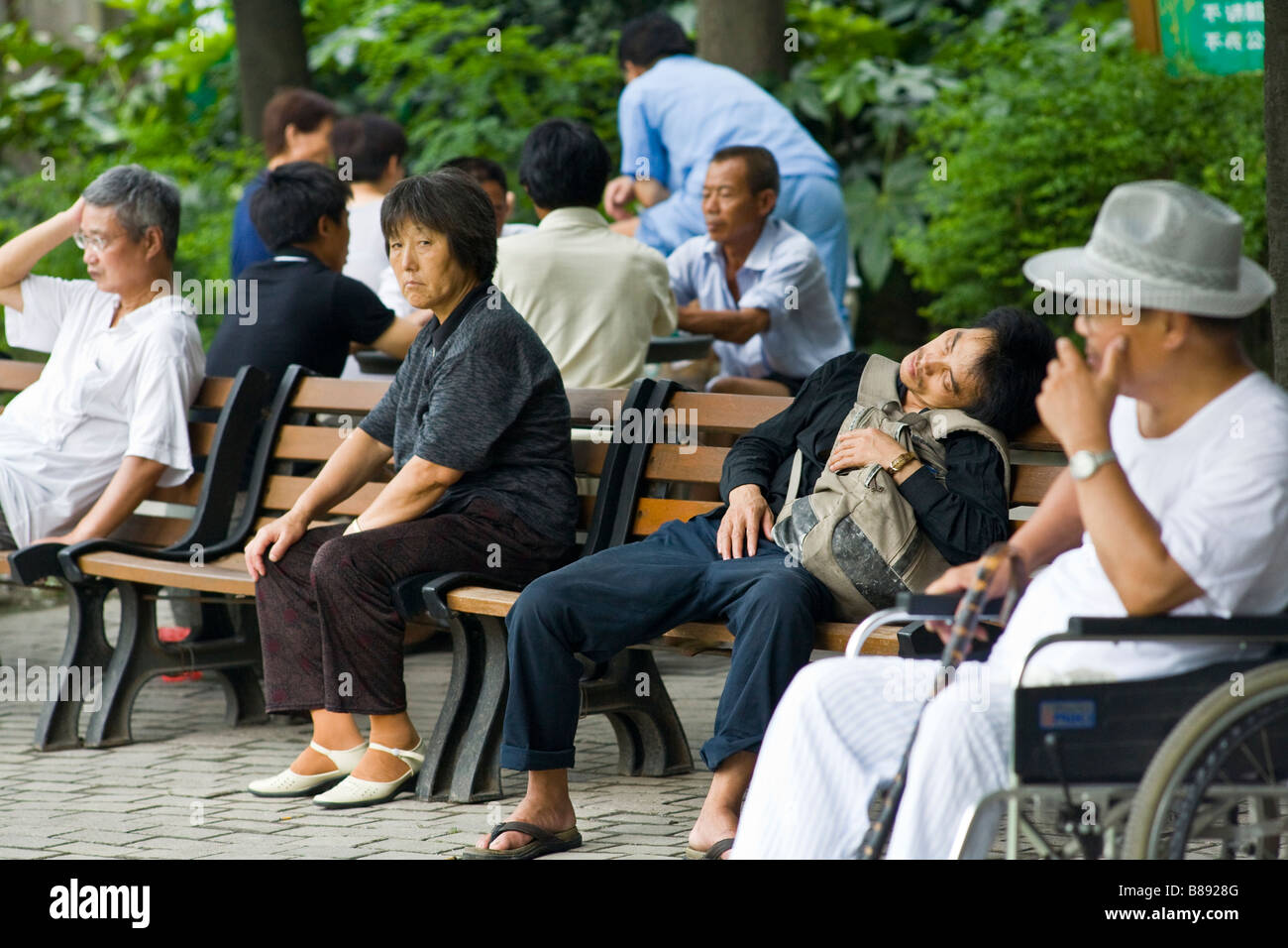 Il popolo cinese in appoggio sul pomeriggio sui banchi del parco del Tempio Jing An Garden, Shanghai in Cina Foto Stock