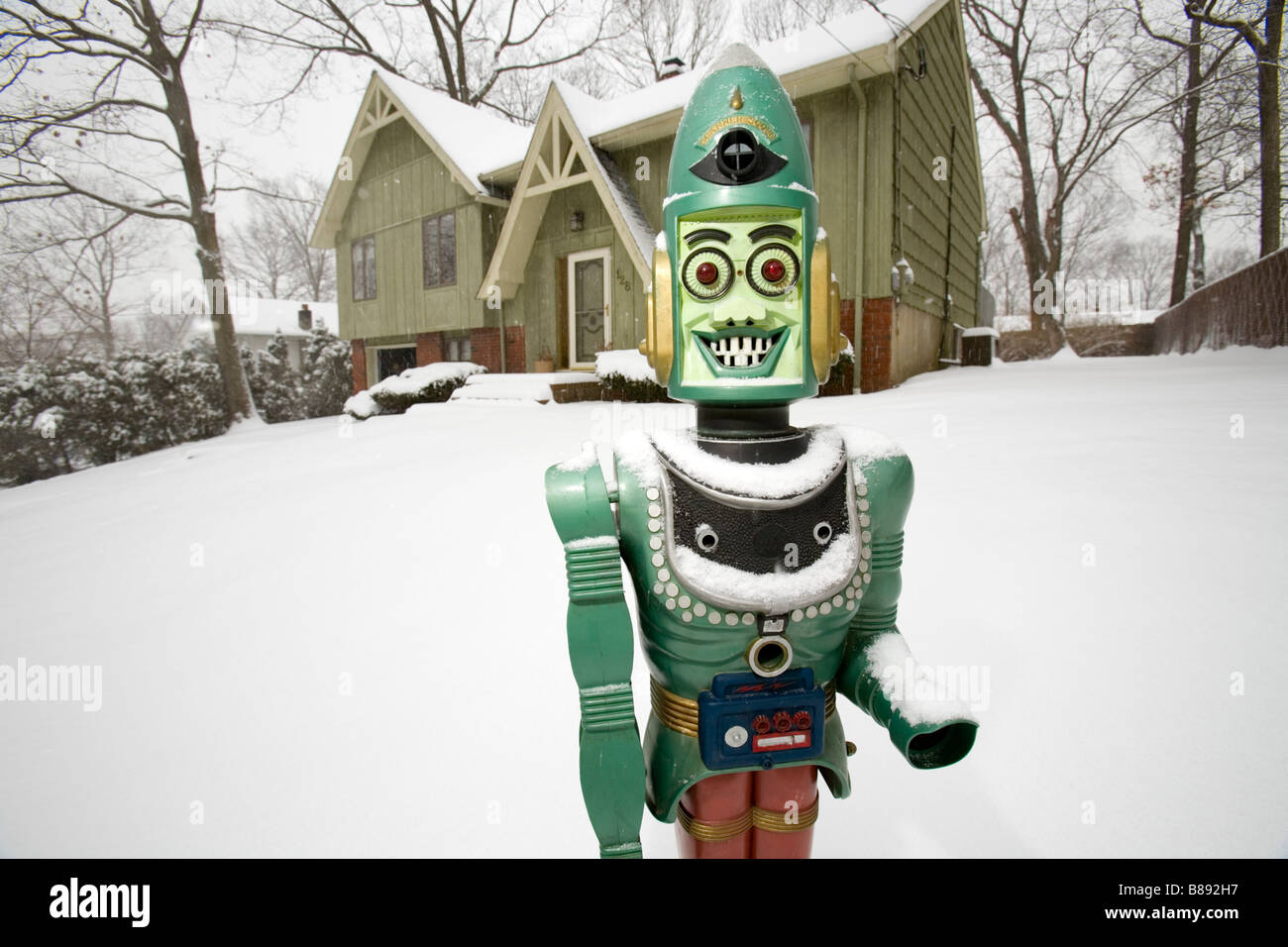 Un robot giocattolo si erge al di fuori di una casa privata nella neve. Foto Stock