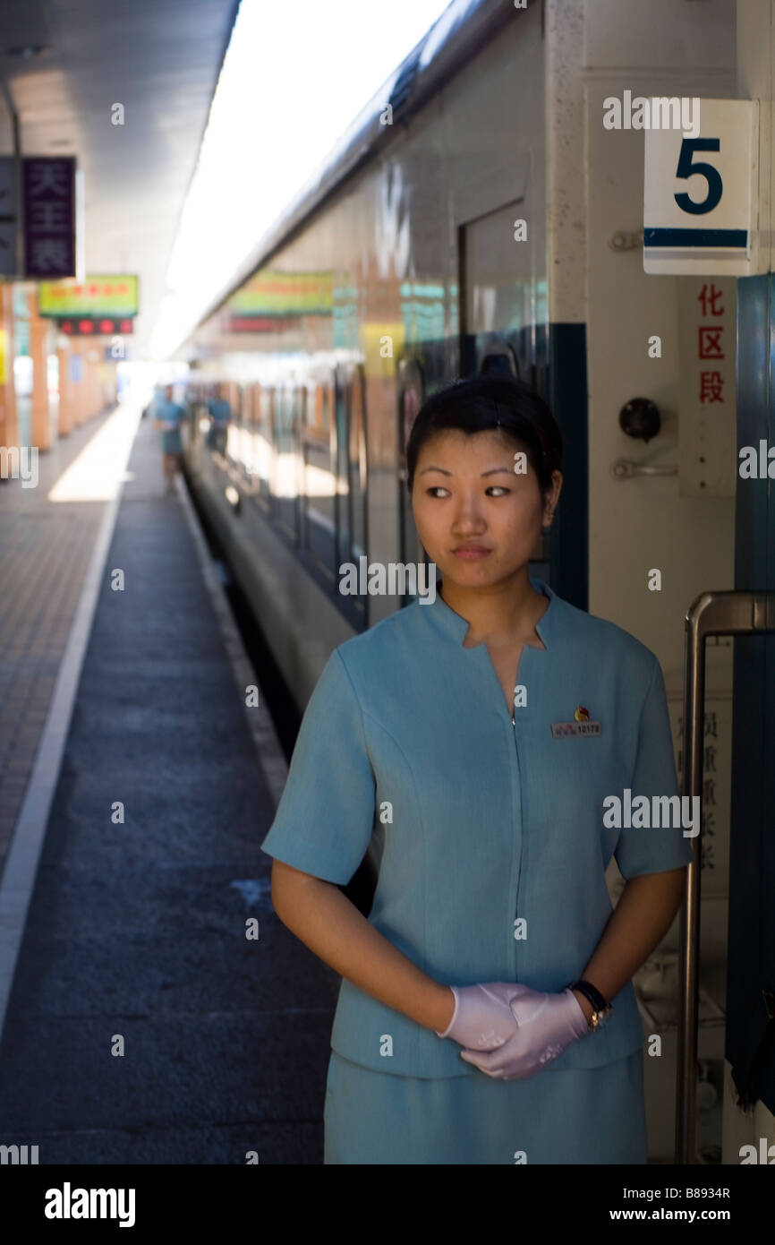 Compartimento del treno hostess attende i passeggeri sulla piattaforma di dalla stazione ferroviaria di Shanghai. Foto Stock