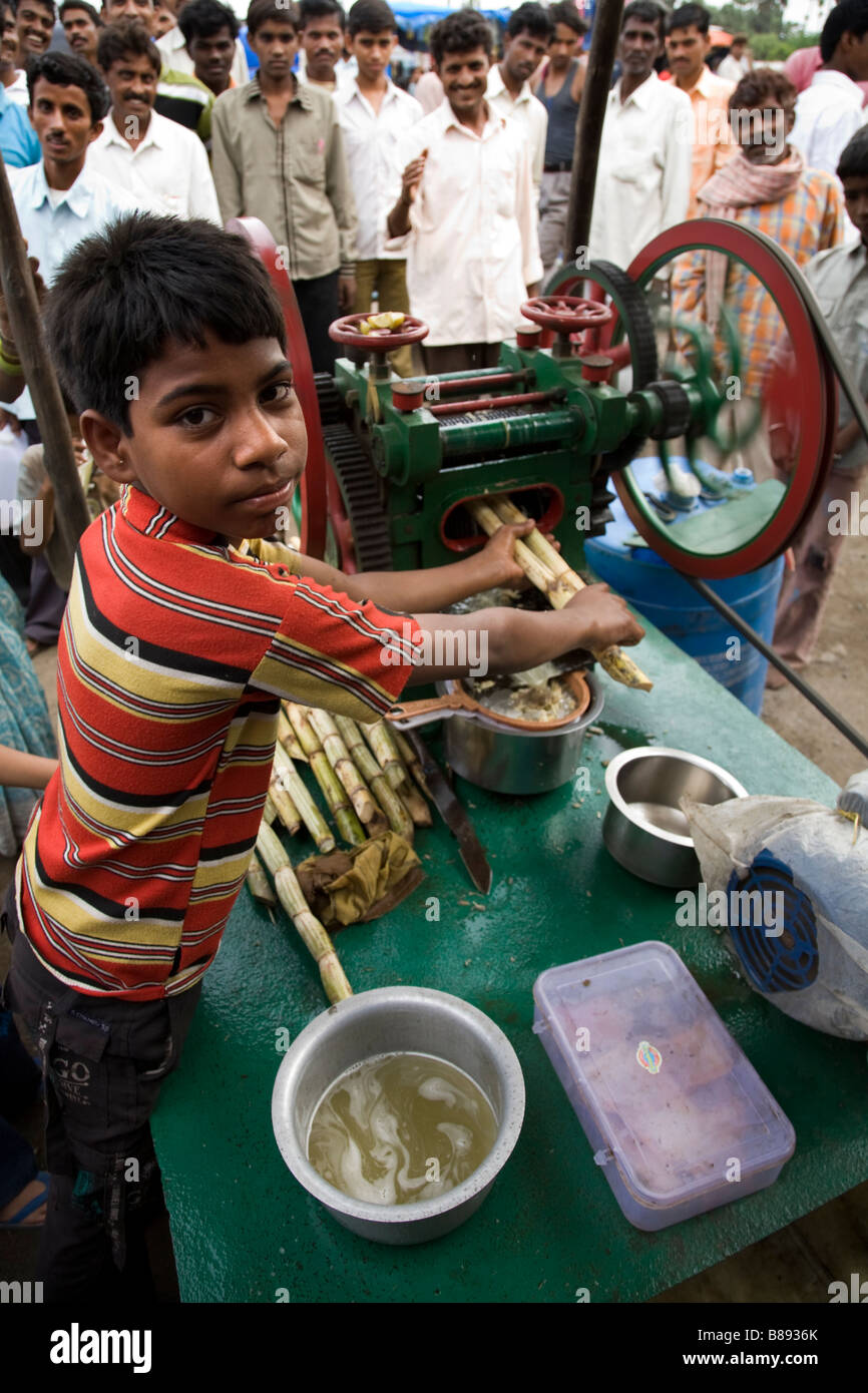 Ragazzo con zucchero di canna e una macchina di frantumazione. Strada del mercato. Hazira, Surat, Gujarat. India. Foto Stock