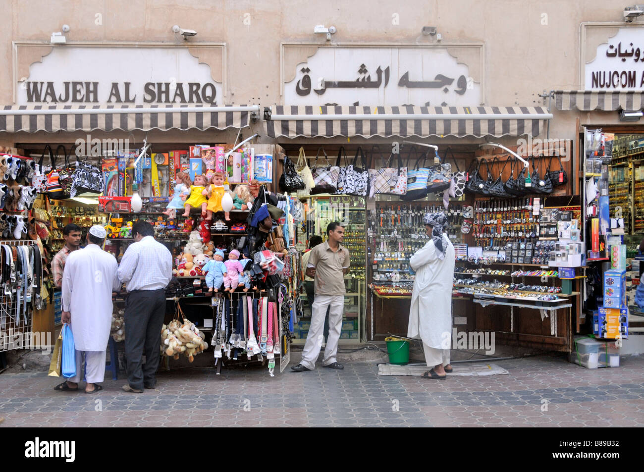 People & Dubai shopping Street scene piccoli negozi e negozi esposizione vendita di merci variegate per gli acquirenti Emirati Arabi Uniti Emirati Arabi Uniti Medio Oriente Foto Stock