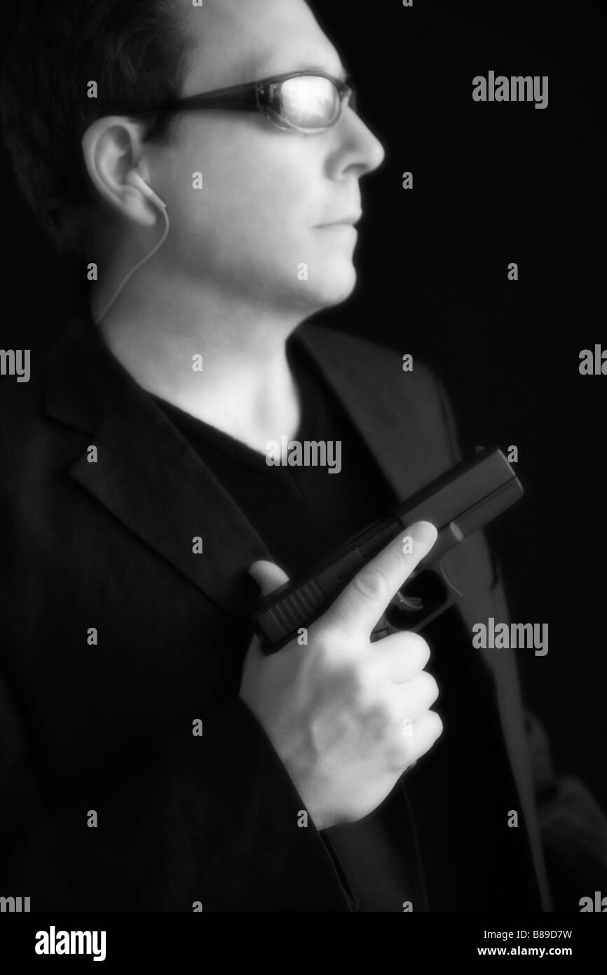 Ritratto di un uomo che indossa gli occhiali da sole e in possesso di una pistola. (Soft focus effetto di incandescenza) Foto Stock