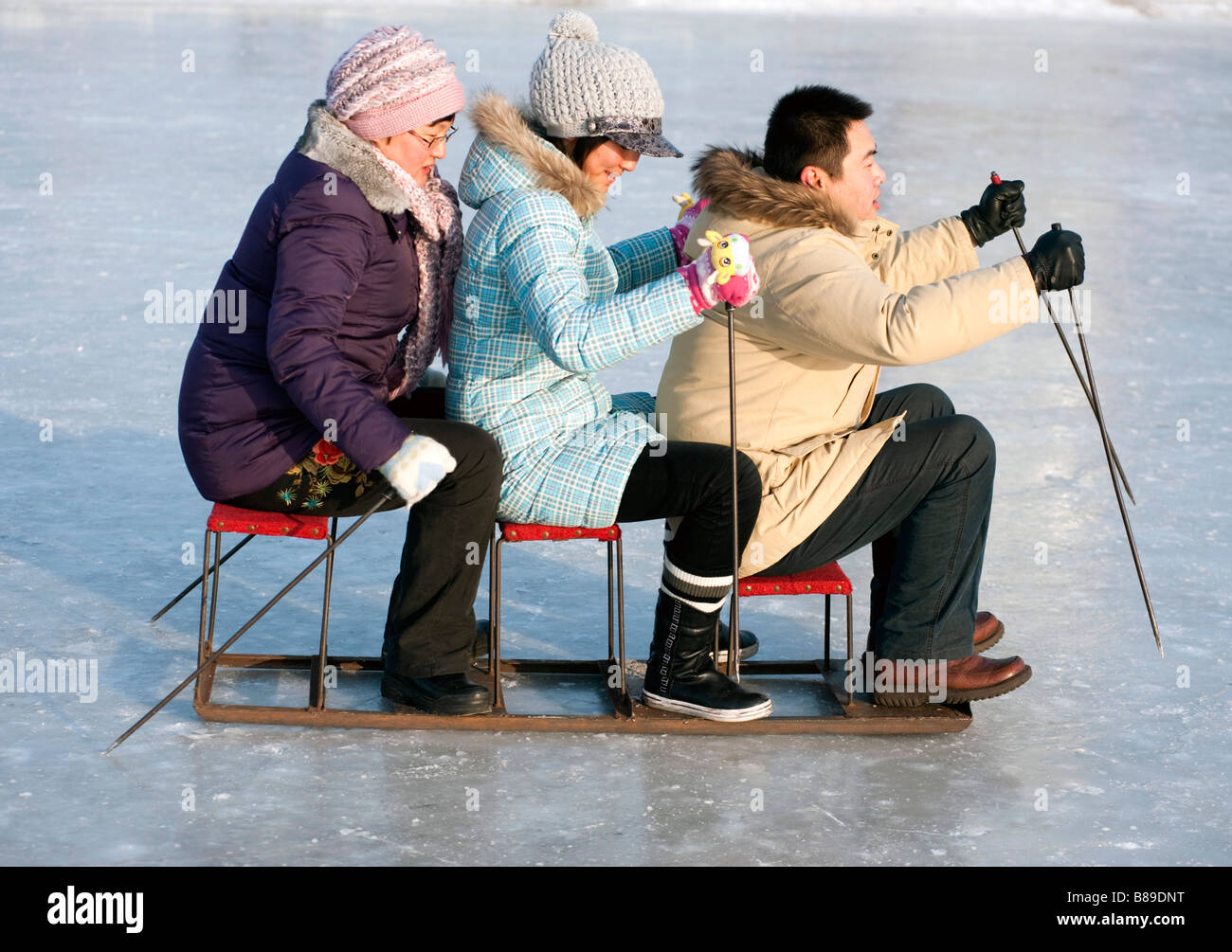 Tre amici su una slitta sulla pista di pattinaggio su ghiaccio congelato sul fiume Songhua ad Harbin durante l'inverno la Cina 2009 Foto Stock