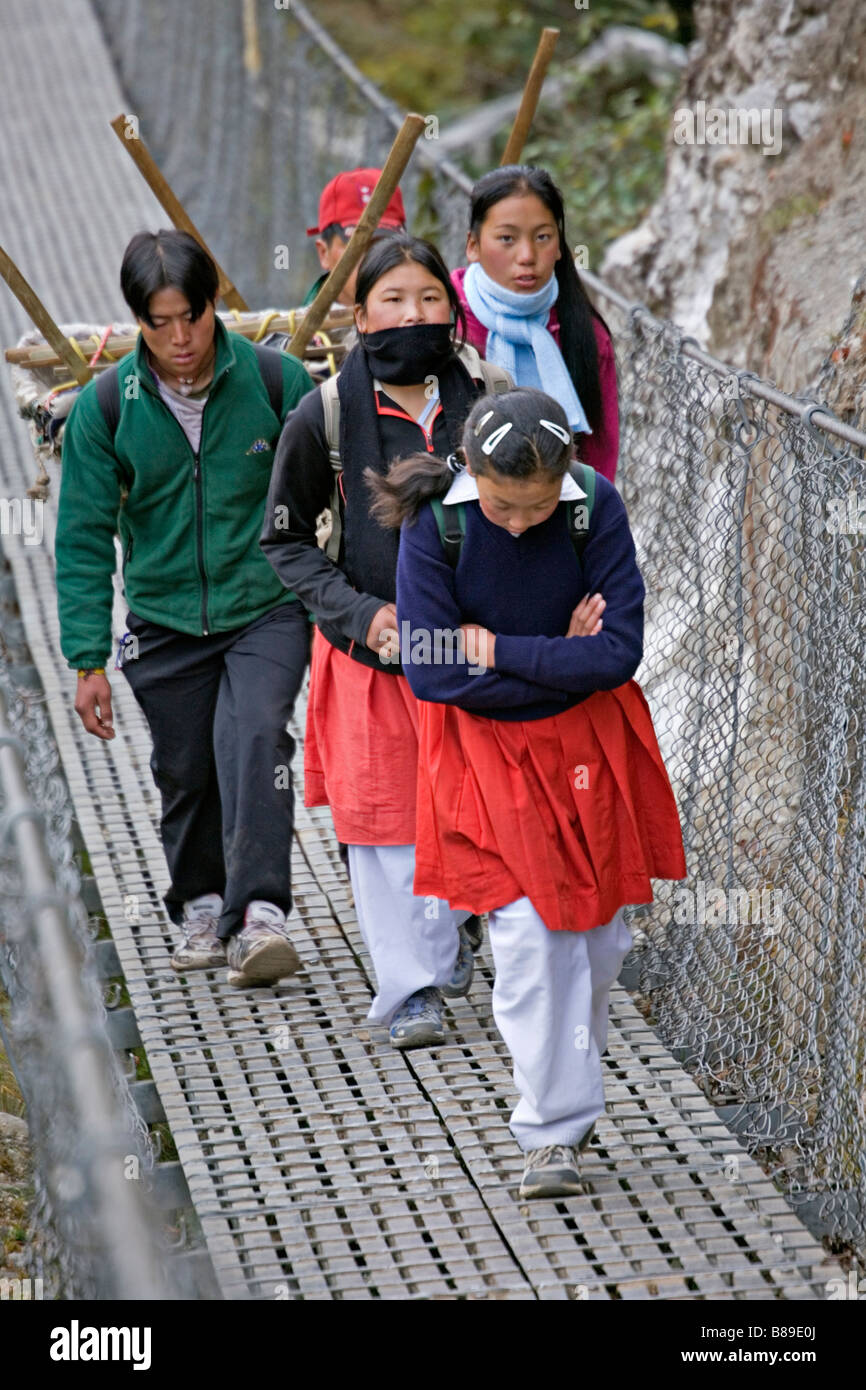 Il nepalese bambini vestiti in uniformi di scuola passando sospensione ponte vicino a Lukla nella regione Solokhumbu Nepal Foto Stock