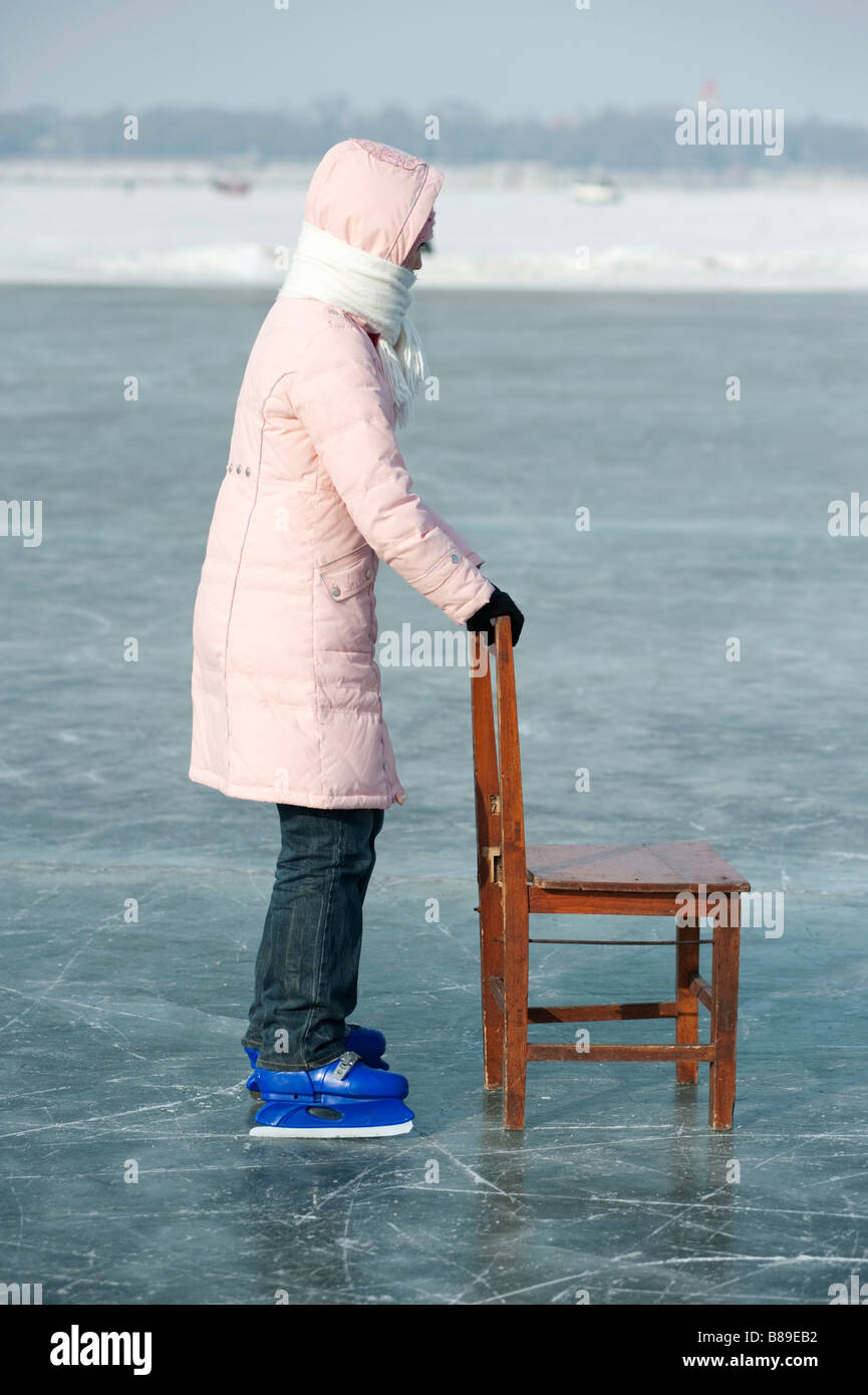 Giovane ragazza cinese imparare a pattinare con sedia in legno per facilitare il bilanciamento su congelati fiume Songhua Harbin Cina 2009 Foto Stock