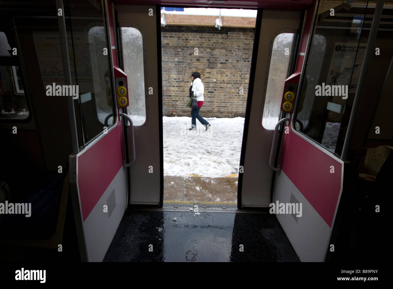 Un pendolare solitario alla stazione di Walthamstow è visibile attraverso le porte dei treni, poiché la neve gelida porta Londra a un arresto. Foto Stock