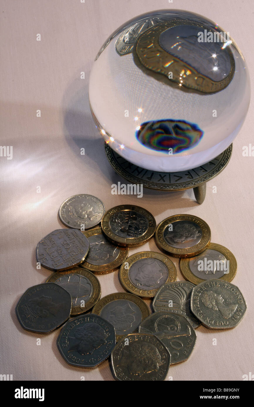 Una fotografia di una sfera di cristallo ingrandimento di una parte di un due pound coin circondato da altre monete di GBP in background. Foto Stock