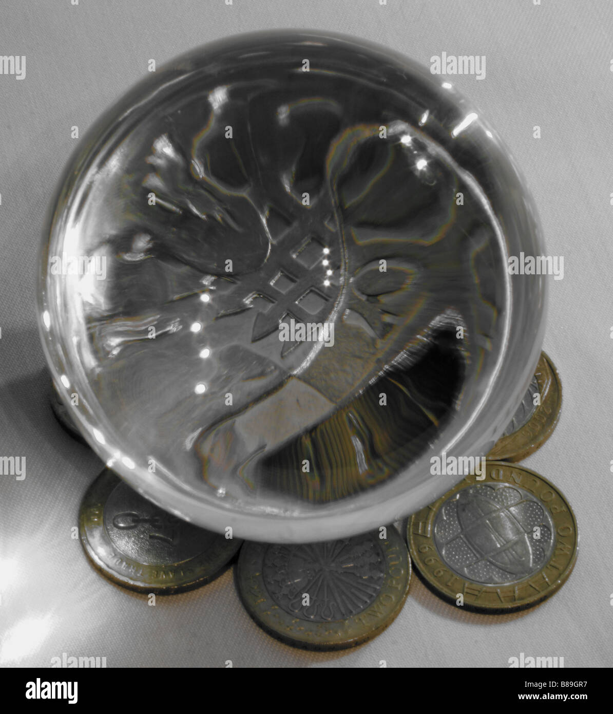 Una fotografia di una sfera di cristallo ingrandimento di una parte di un cinquanta pence pezzo, circondato da due pound GBP monete in background. Foto Stock