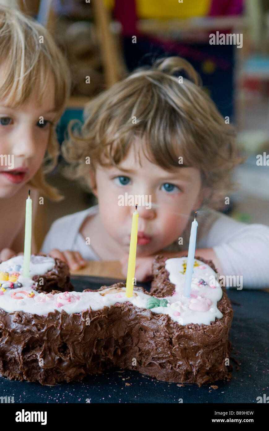 Un giovane ragazzo si brucia candele sulla sua torta di compleanno Foto Stock