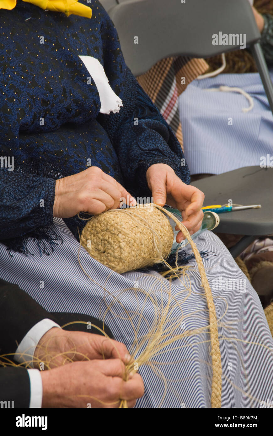Craftswoman in costume tradizionale preparazione di sparto presso la tradizionale fiera di artigianato, Santa Eulalia, Ibiza, Spagna Foto Stock