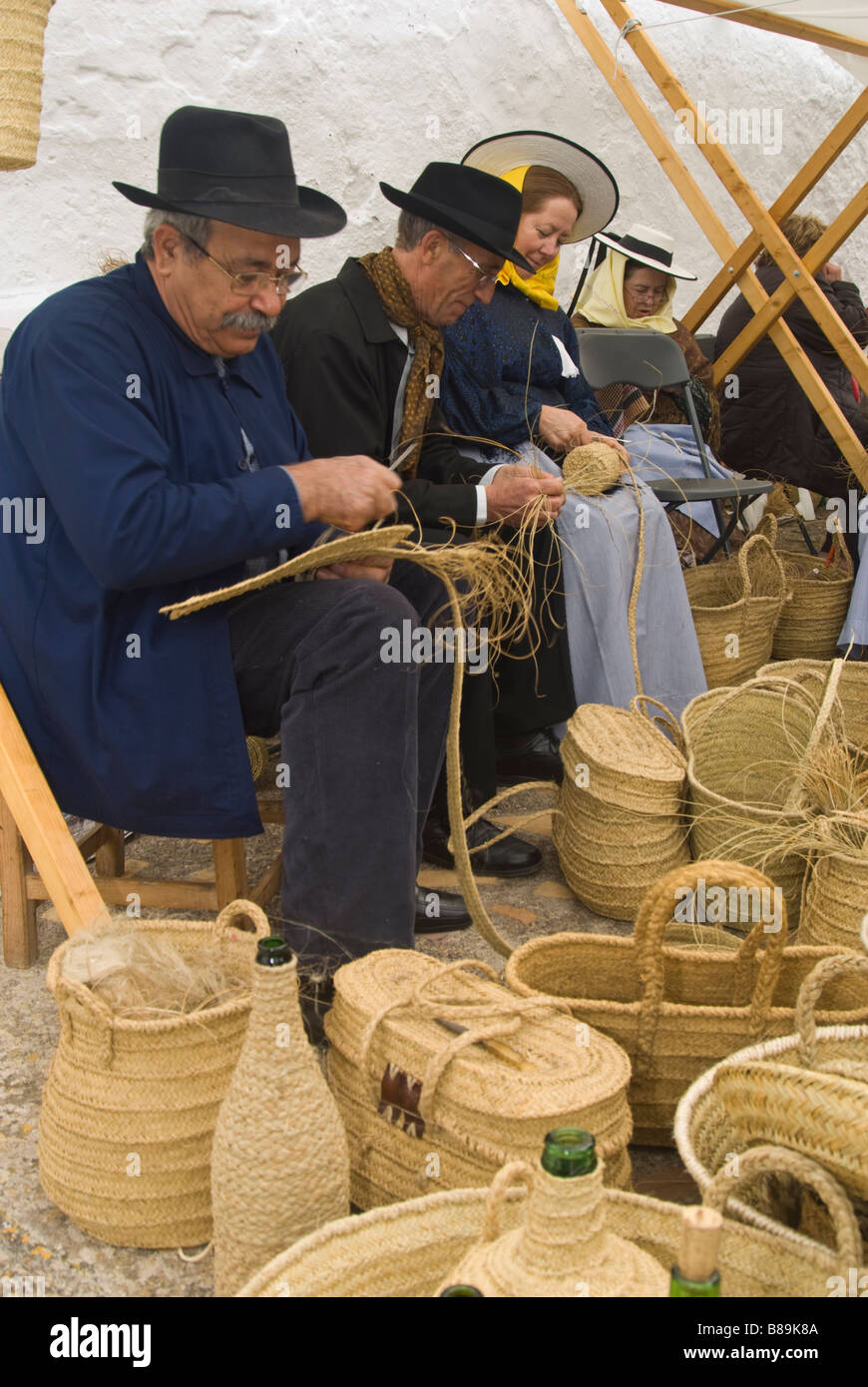 Gli artigiani in costume tradizionale cesti che fanno fuori di sparto presso la tradizionale fiera di artigianato, Santa Eulalia, Ibiza, Spagna Foto Stock
