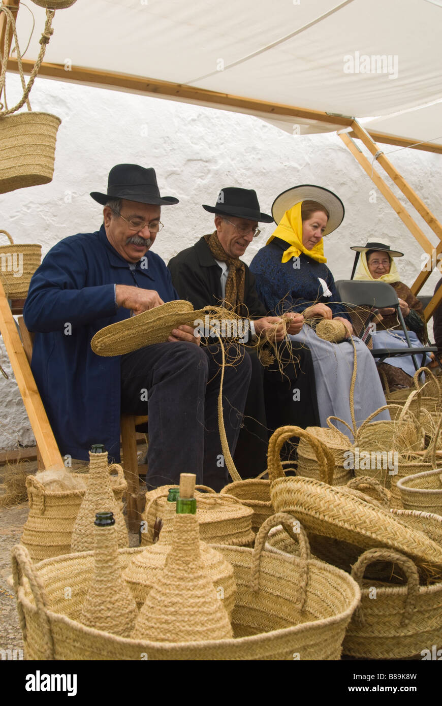 Gli artigiani in costume tradizionale cesti che fanno fuori di sparto presso la tradizionale fiera di artigianato, Santa Eulalia, Ibiza, Spagna Foto Stock