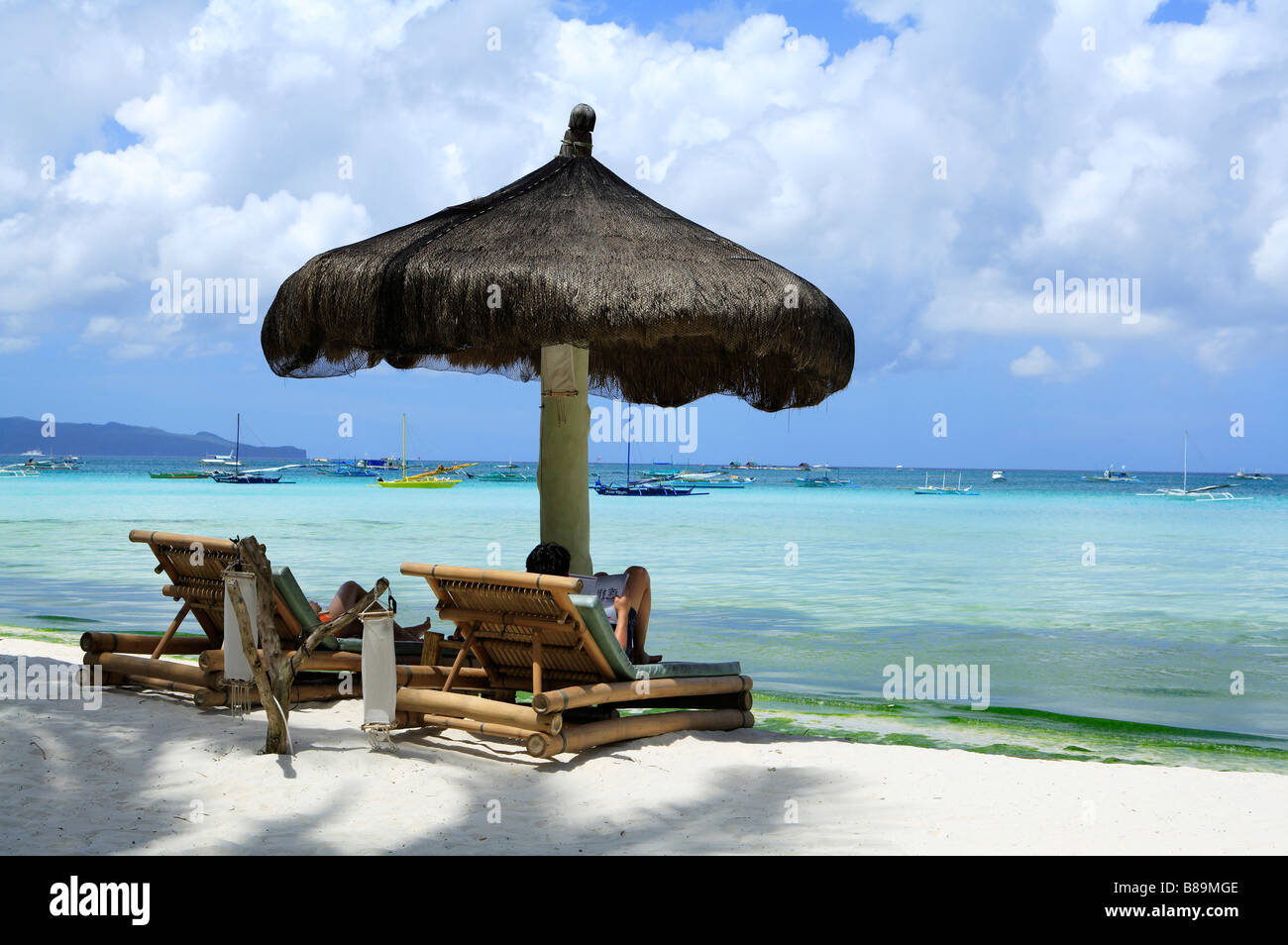 Persone rilassante sulla spiaggia sedia sotto l'ombrellone Foto Stock