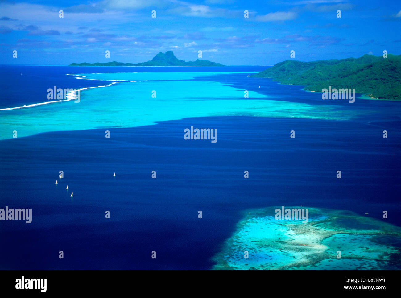 Barche a vela in laguna di Tahaa con isola di Bora Bora in distanza in Polinesia francese Foto Stock